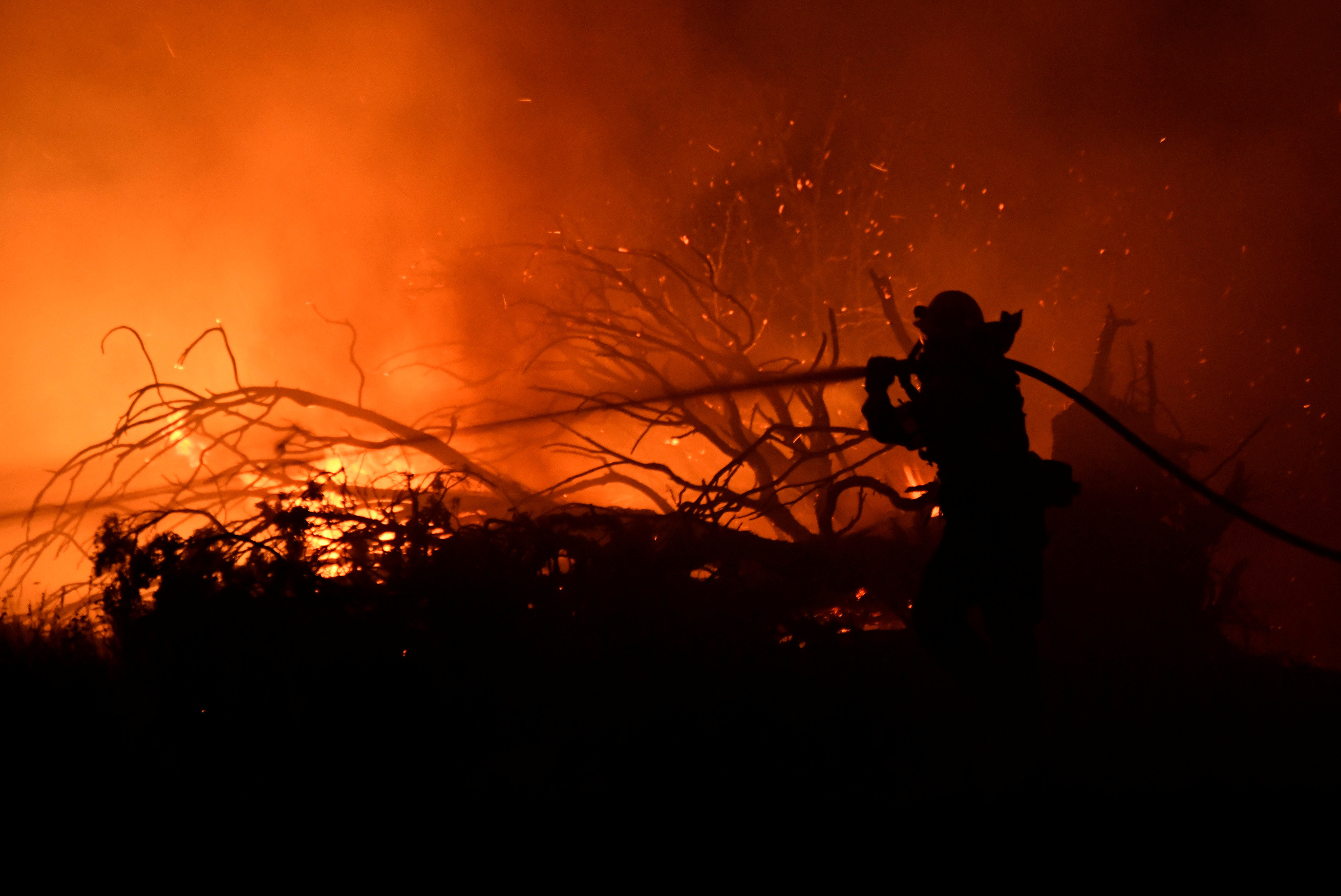 Los Angeles County firefighter holds back the flames to save homes Saturday morning from the Bobcat Fire in Juniper Hills, California, U.S., September 19, 2020. REUTERS/Gene Blevins