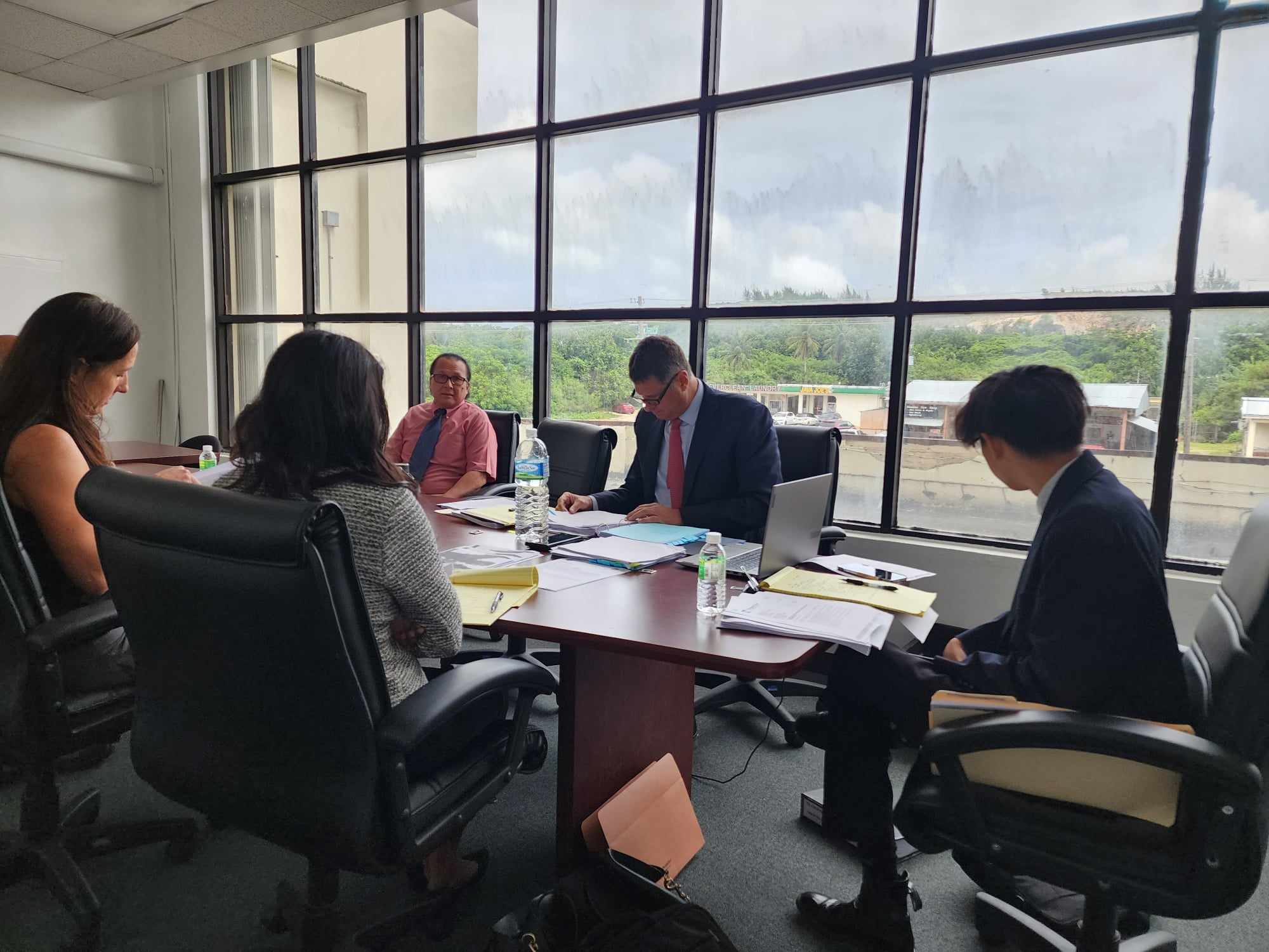 Department of Public Lands Hearing Officer Ramon Dela Cruz, third left, background, presides over an evidentiary hearing in the DPL conference room as Assistant Attorney General Ali Nelson, left, and Rota Resort legal counsel Colin Thompson, center, review  documents on Friday. Also in photo is Assistant Attorney General Vina Seelam.