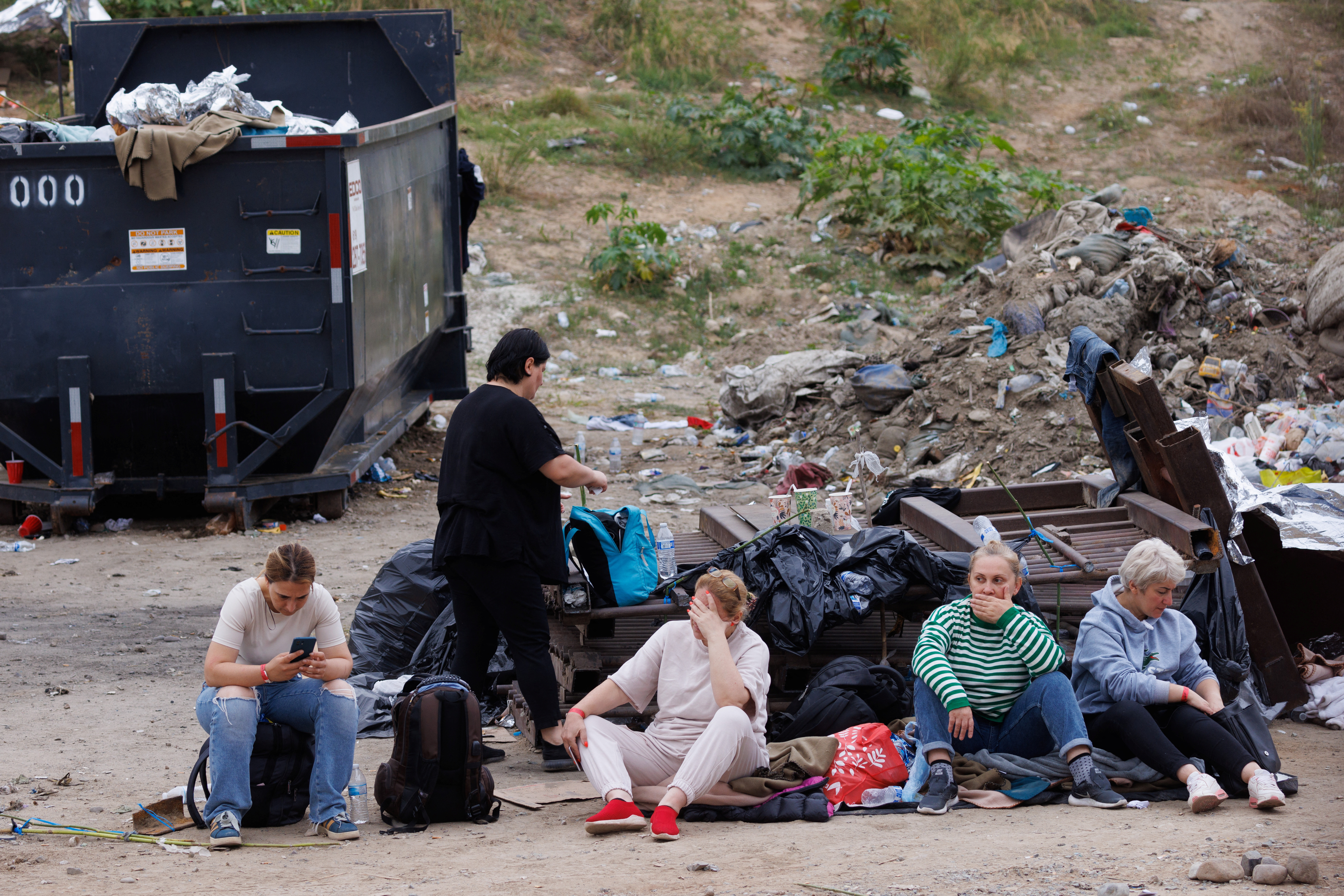 Migrants from Georgia await processing by U.S immigration as they wait between the primary and secondary border fences between Mexico and the United States in San Diego, U.S., September 14, 2023. REUTERS/Mike Blake