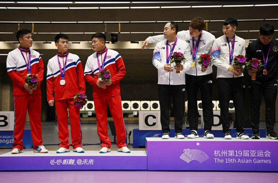 South Korean  gold medalists Ha Kwang-chul, Jeong You-jin and Your Bin Kwak stand on the podium after the Men's Team 10m Running Target Mixed event alongside North Korean silver medalists Kwon Kwang-il, Pak Myong-won and Songjun Yu at the Asian Games in Hangzhou, China, Sept. 25, 2023
