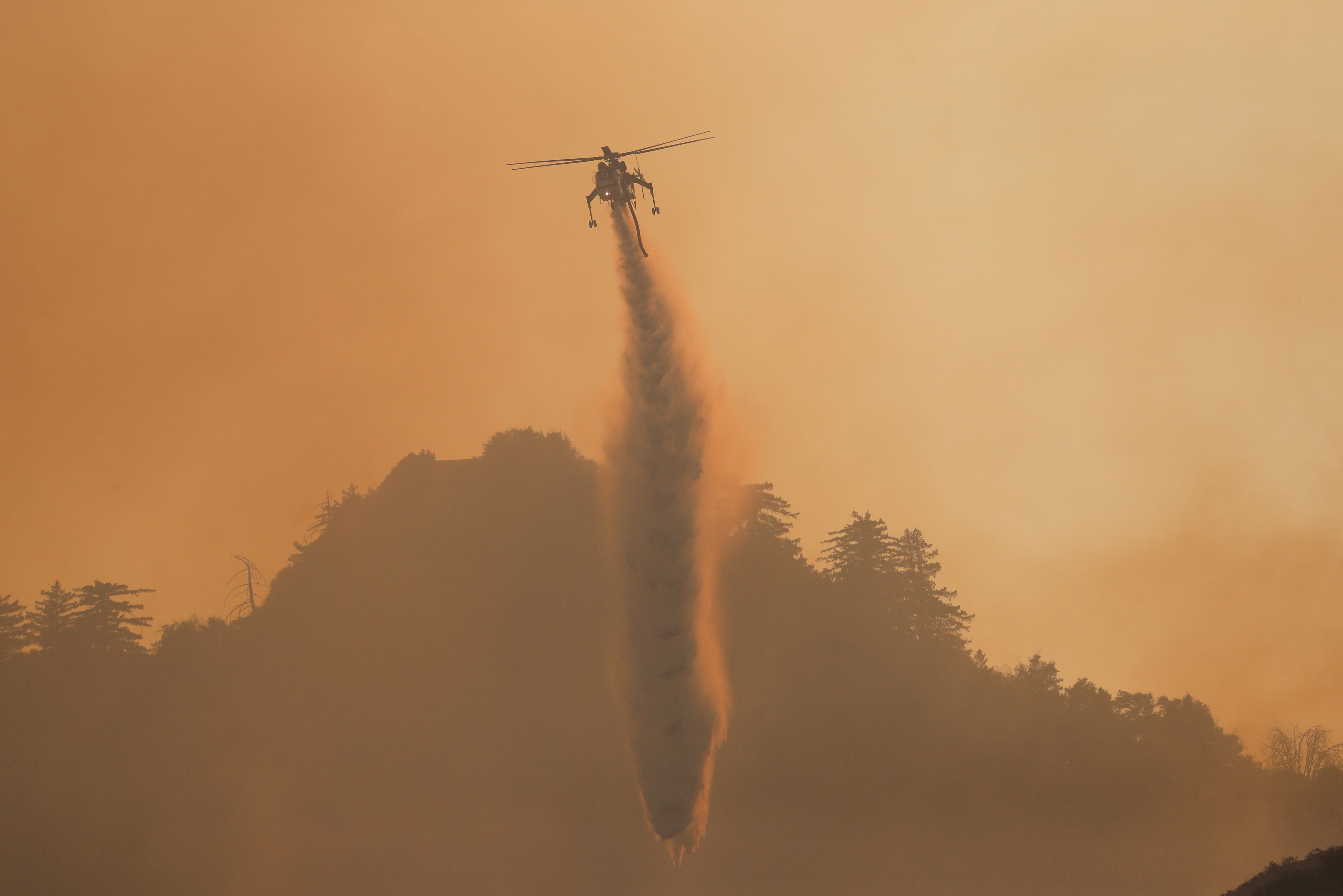 A helicopter makes a water drop over the Bobcat Fire burning near Mount Wilson in the Angeles National Forest, near Los Angeles, U.S., September 23, 2020. REUTERS/Mario Anzuoni/File Photo