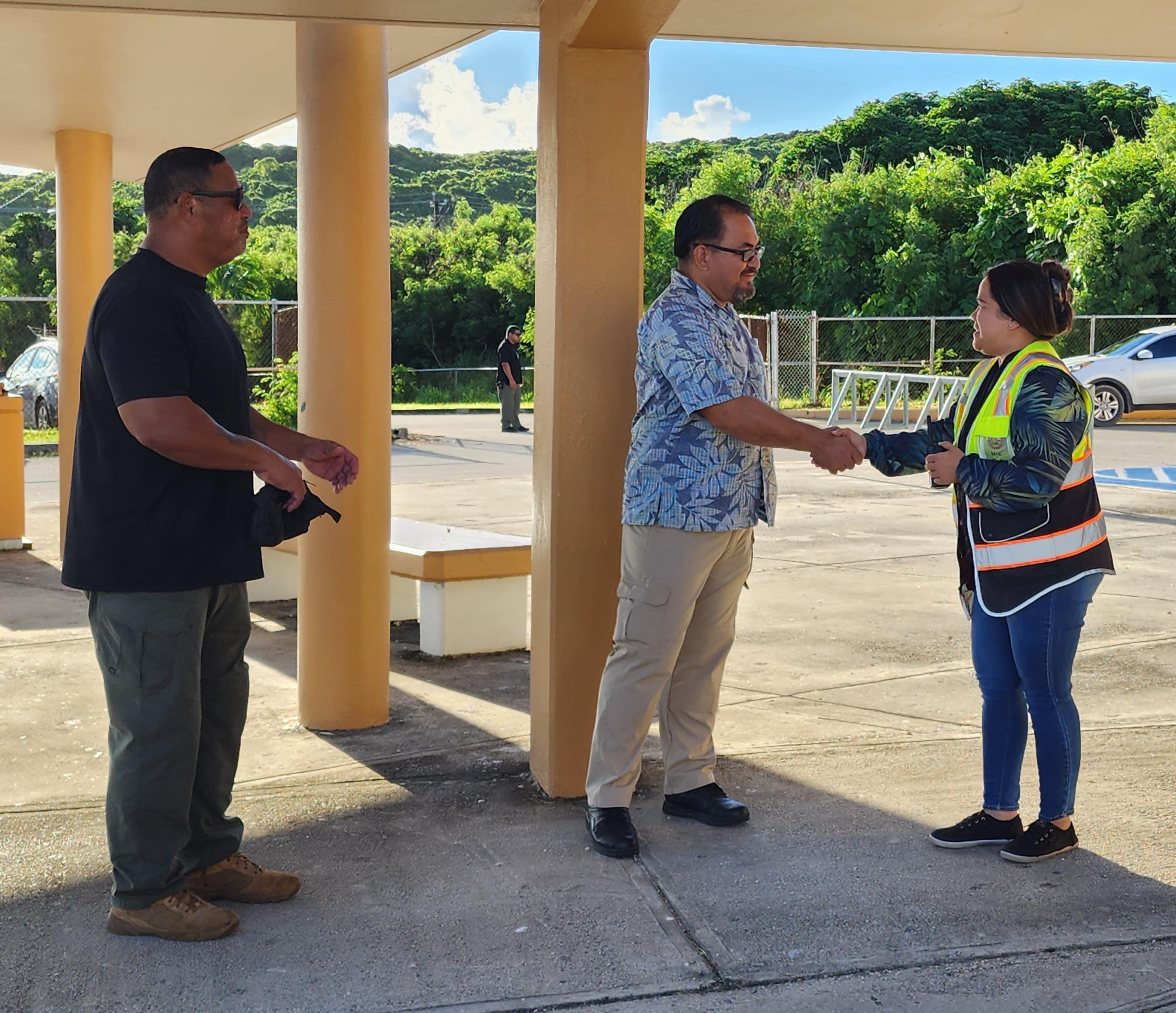 Department of Public Safety Commissioner Clement Bermudes, center, shakes hands with Chacha Ocean View Middle School Principal Carla Sablan on Friday morning while DPS-Special Operation Group Commander Joe Saures looks on.