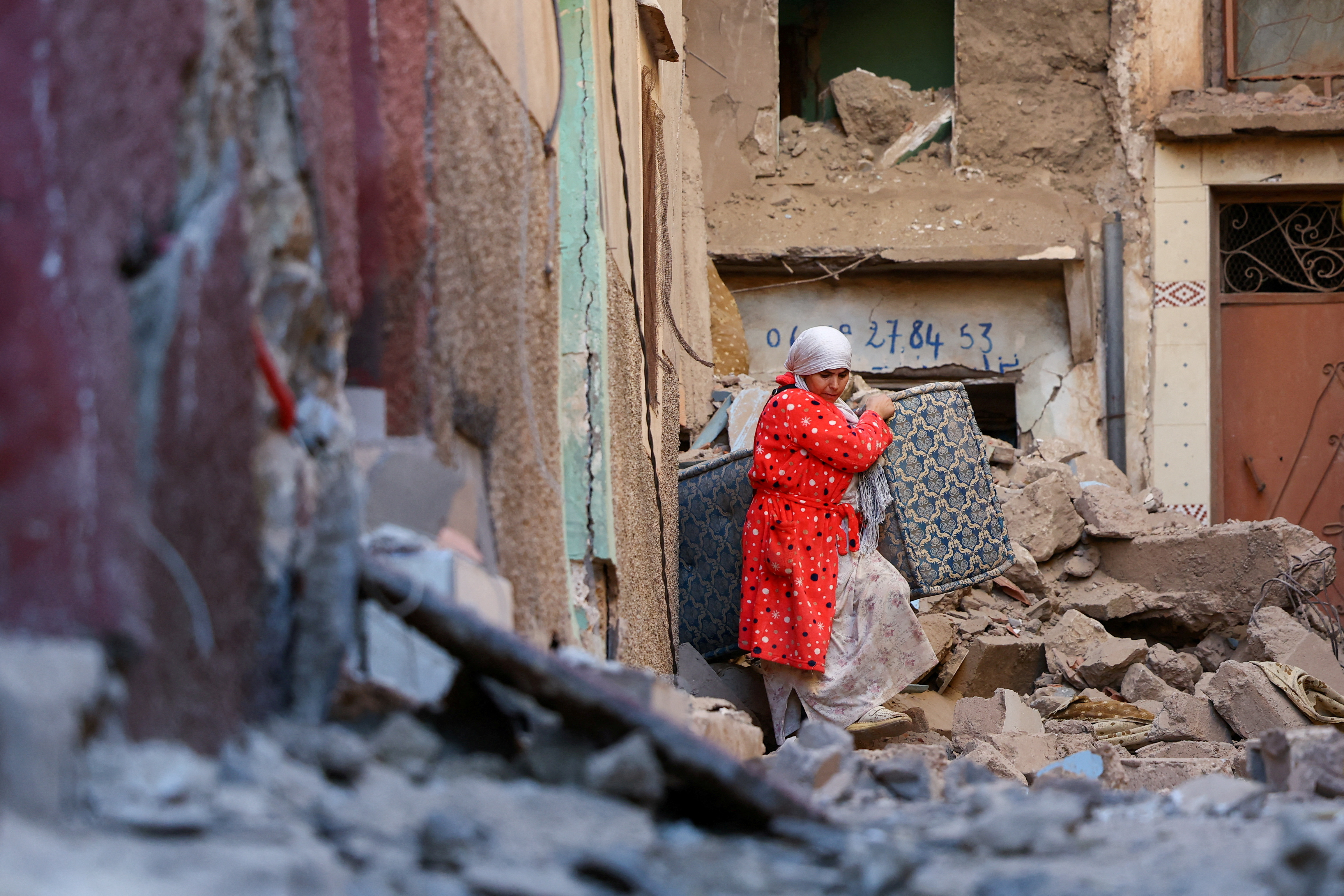A woman carries belongings out of a damaged building, in the aftermath of a deadly earthquake in Moulay Brahim, Morocco, September 10, 2023. REUTERS/Hannah McKay