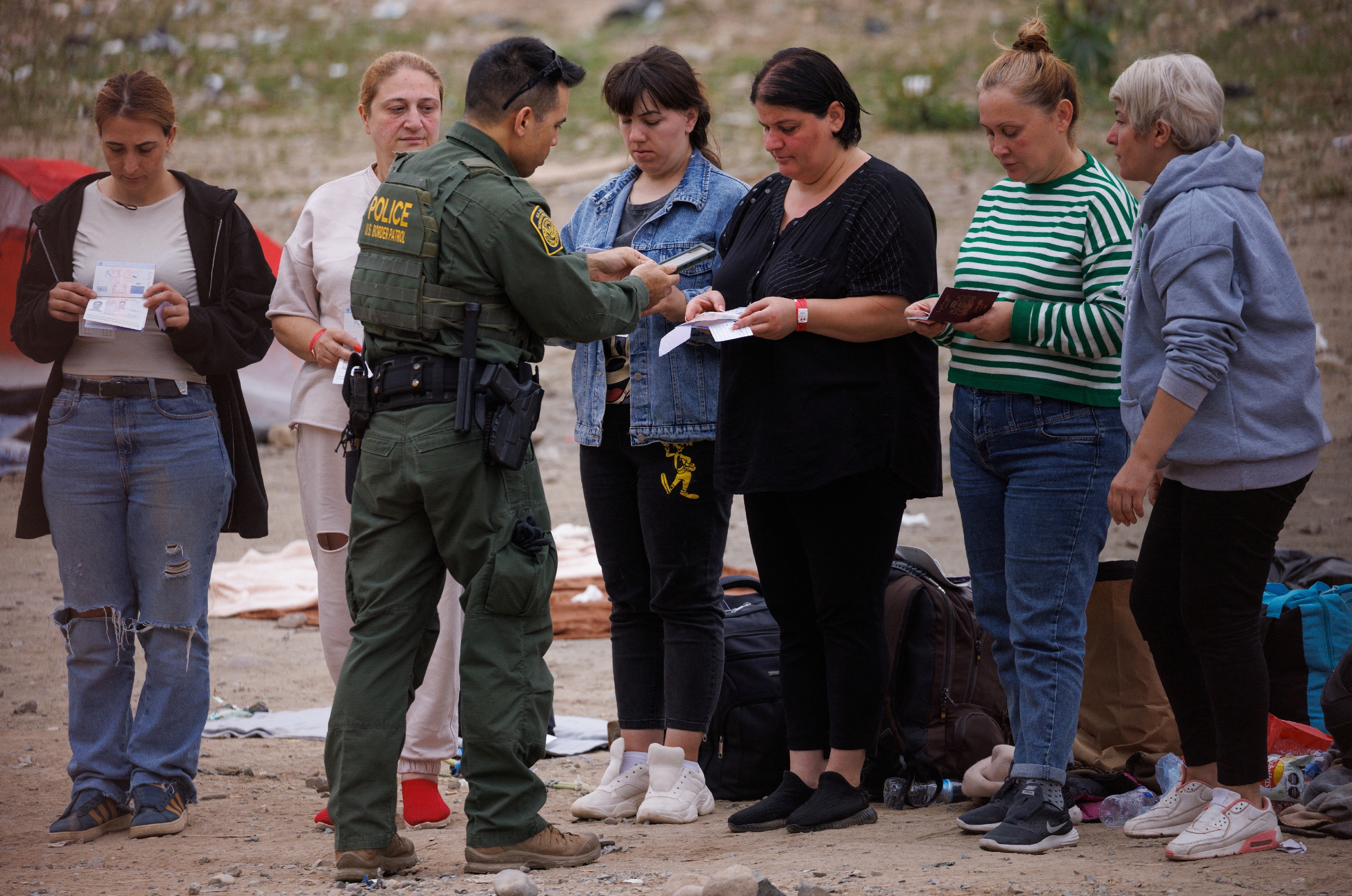 Migrants from Georgia have their pictures taken by a U.S. border patrol agent as they are collected from between the two border walls separating the U.S. and Mexico in San Diego, U.S., September 14, 2023. 