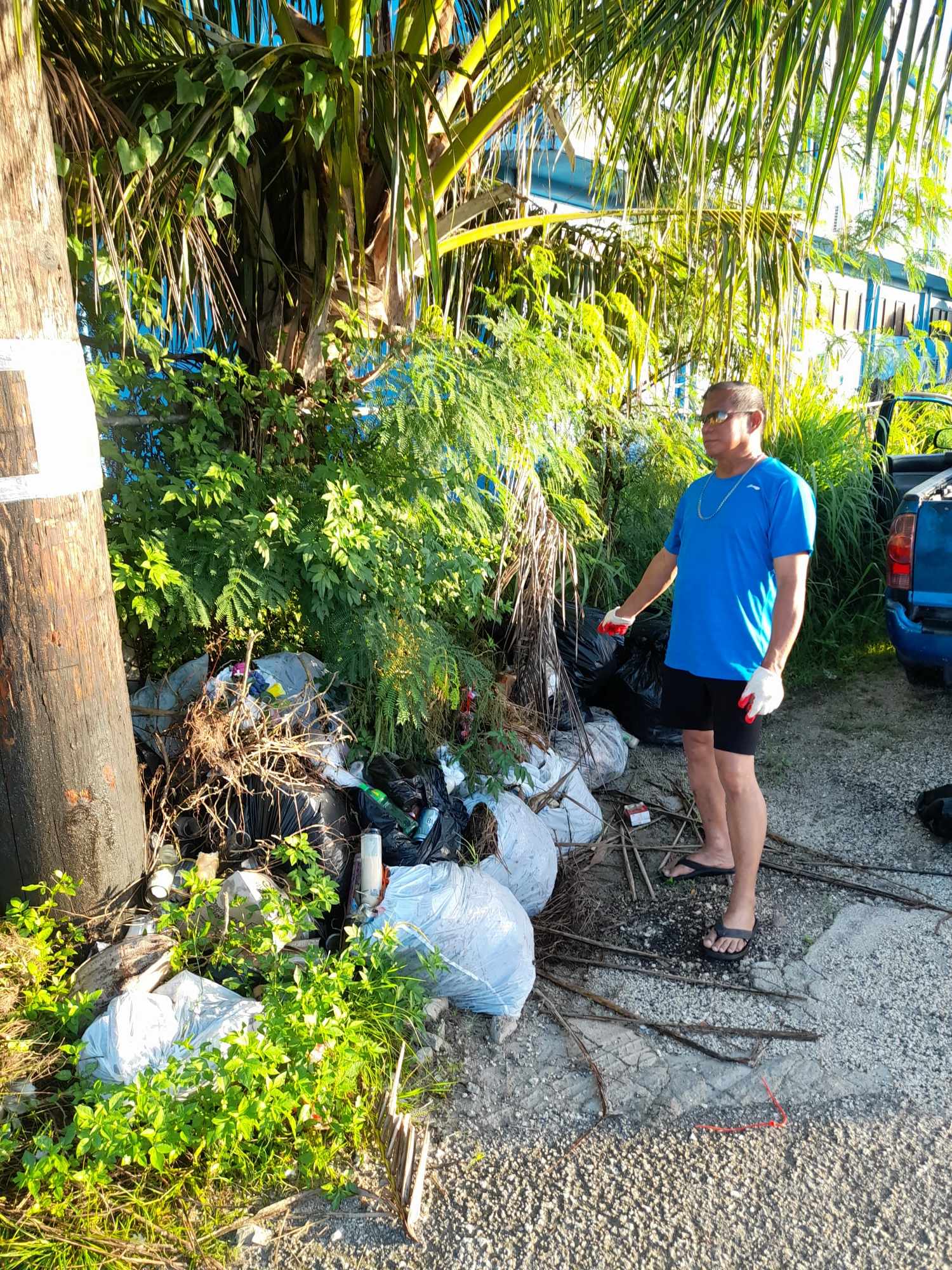Max Aguon points at illegally dumped trash at the Chalan Kanoa cemetery.