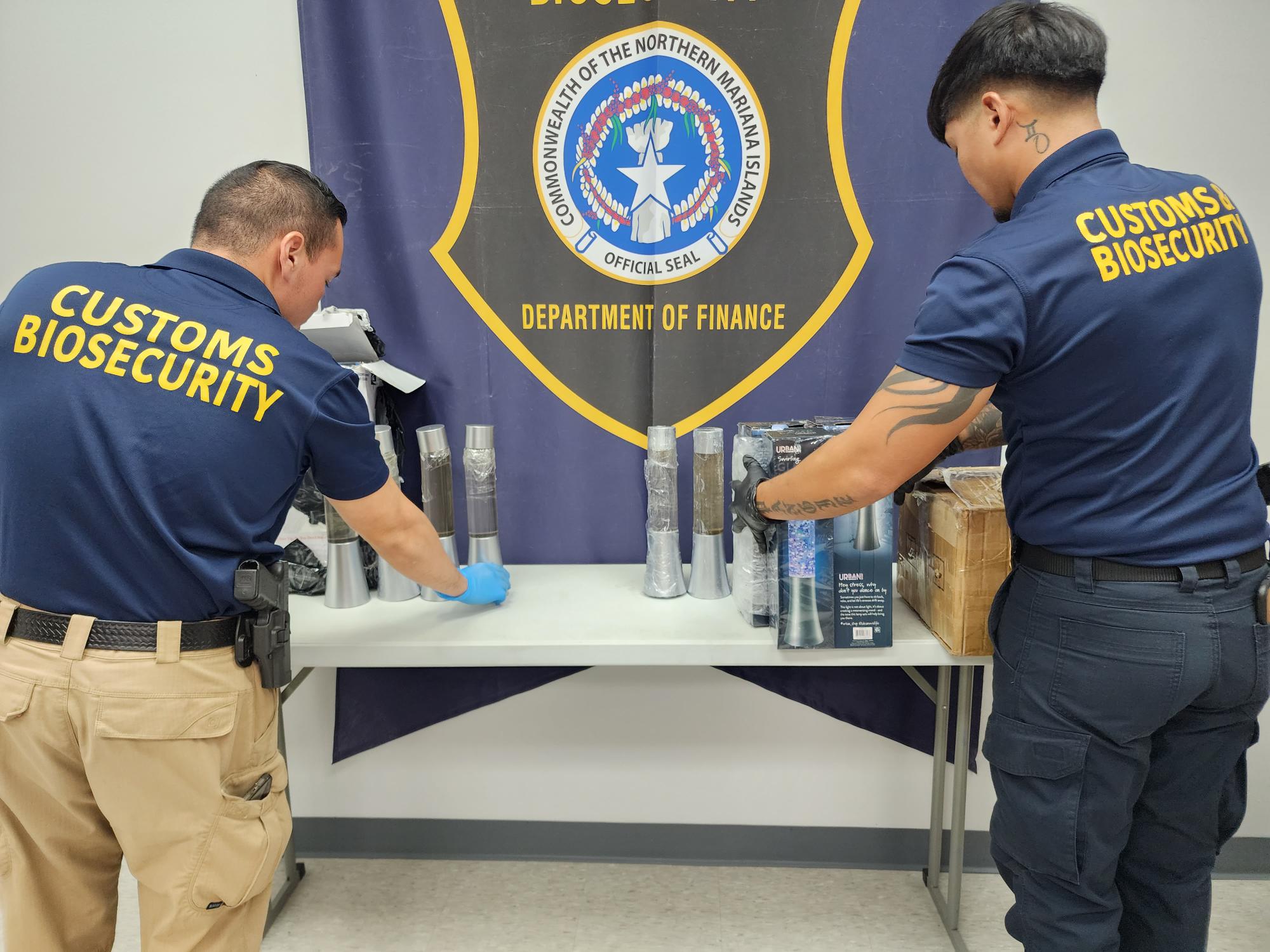 Division of Customs and Biosecurity officers are seen Thursday with the decorative lamps that contained the liquid methamphetamine.