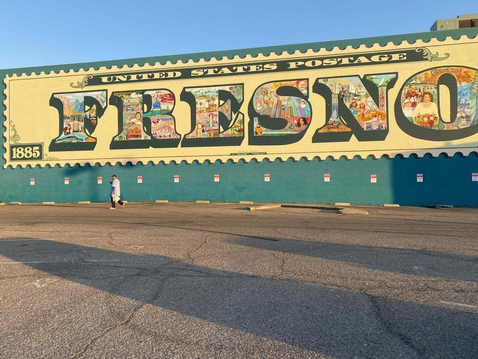 A pedestrian walks by a mural depicting the history, culture and economy of the California Central Valley city of Fresno, California on February 24, 2020. 