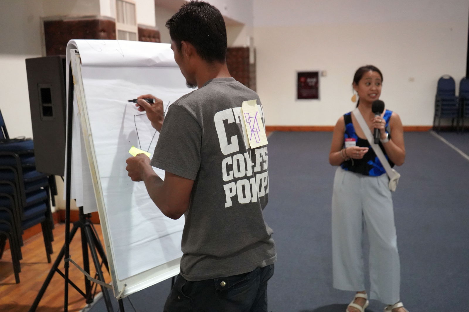 Dr. Tabitha Espina, director of writing at University of Washington Tacoma, guides an exercise in communication at the Pohnpei Farmer Focus Conference on July 28, 2023. The conference participants were tasked to draw a geometric image that was only verbally described to them. 