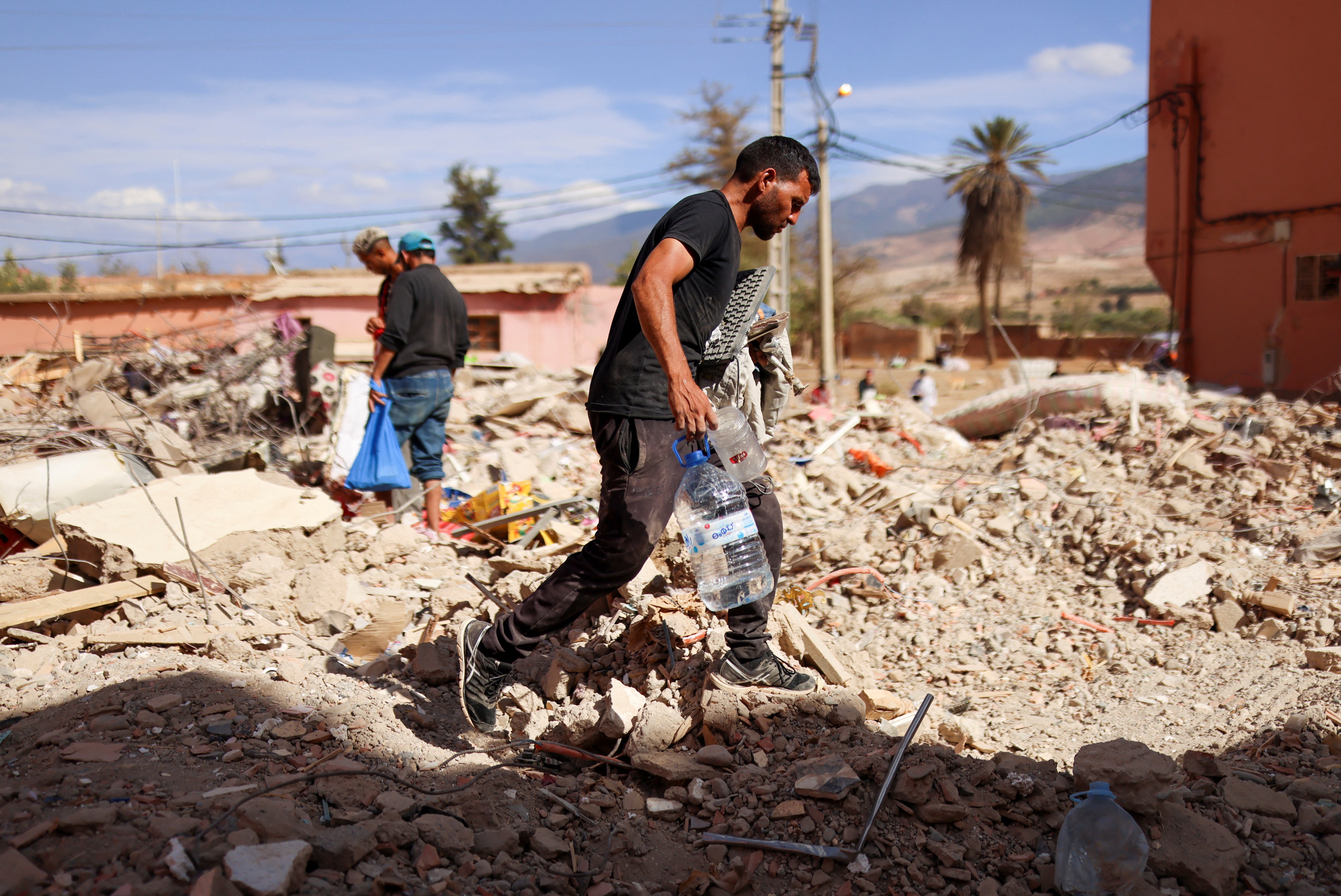 A man walks on the rubble as people look on, in the aftermath of a deadly earthquake, in Amizmiz, Morocco, September 10, 2023. REUTERS/Nacho Doce