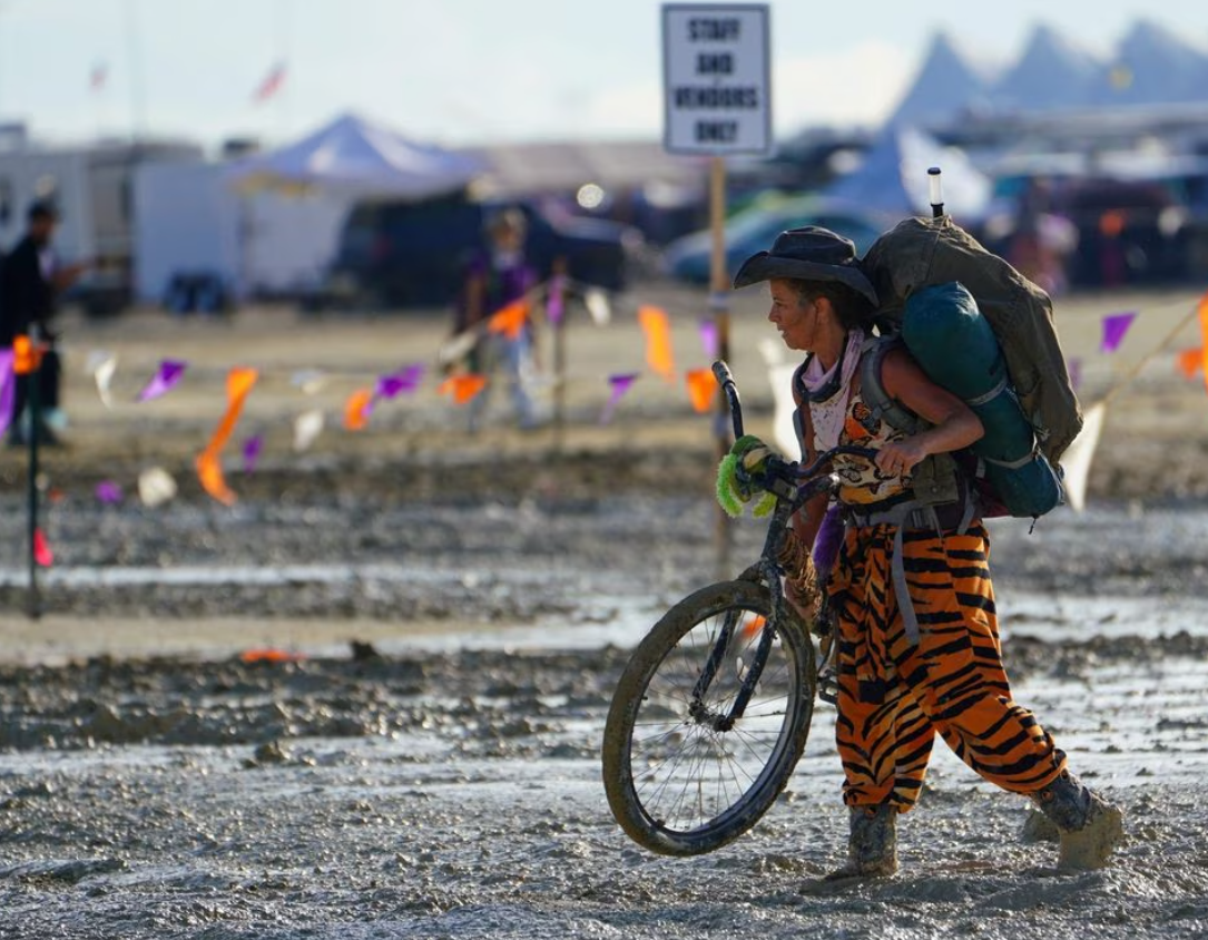 A Burning Man participant walks their bike through the mud near the exit, after a severe rainstorm left tens of thousands of revelers attending the annual festival stranded in mud in Black Rock City, in the Nevada desert Sept. 3, 2023.