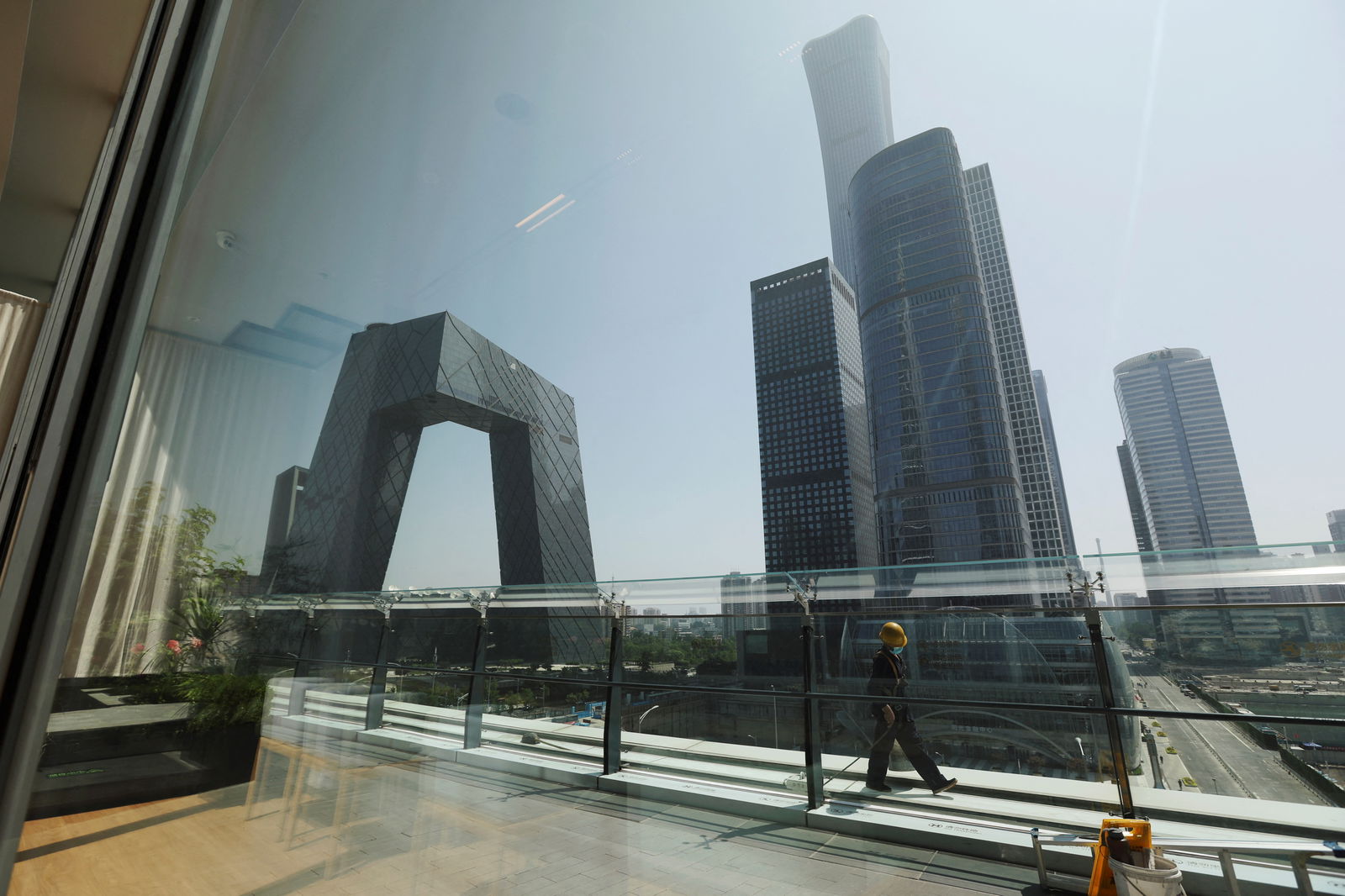 Cap:A cleaning worker is seen through a glass window at a shopping mall in the Central Business District, amid the coronavirus disease outbreak in Beijing, China, June 2, 2022.