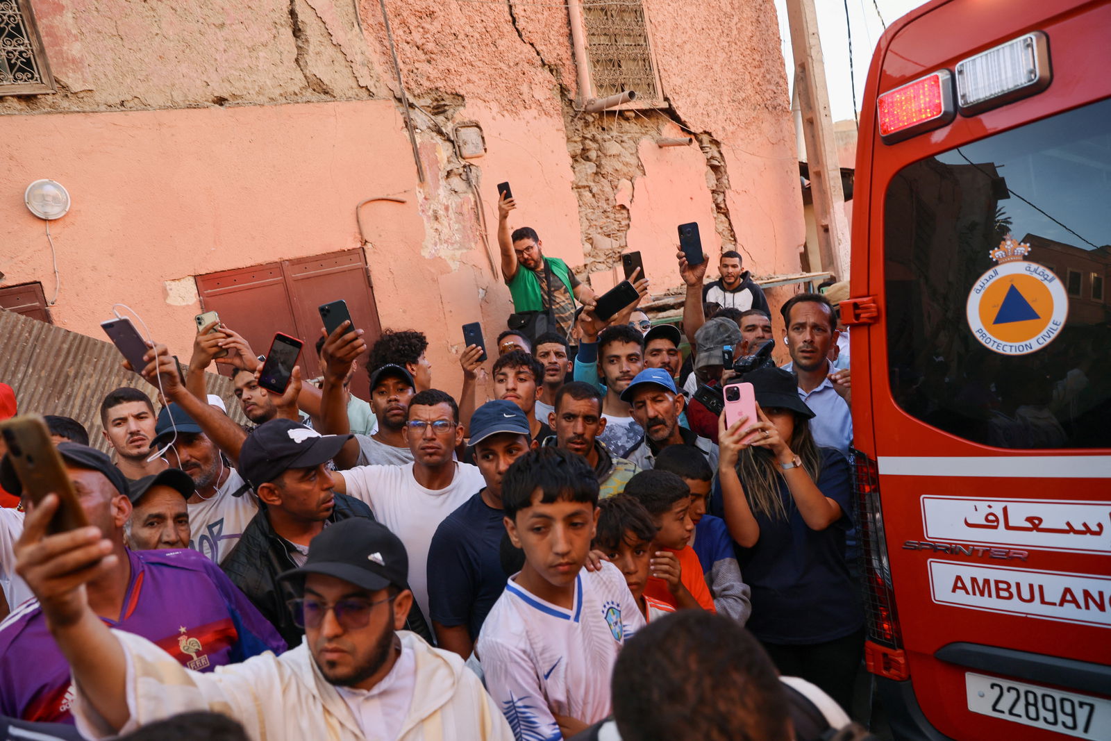 Neighbors take pictures of emergency workers carrying a dead body, in the aftermath of a deadly earthquake, in Amizmiz, Morocco, September 10, 2023. REUTERS/Nacho Doce