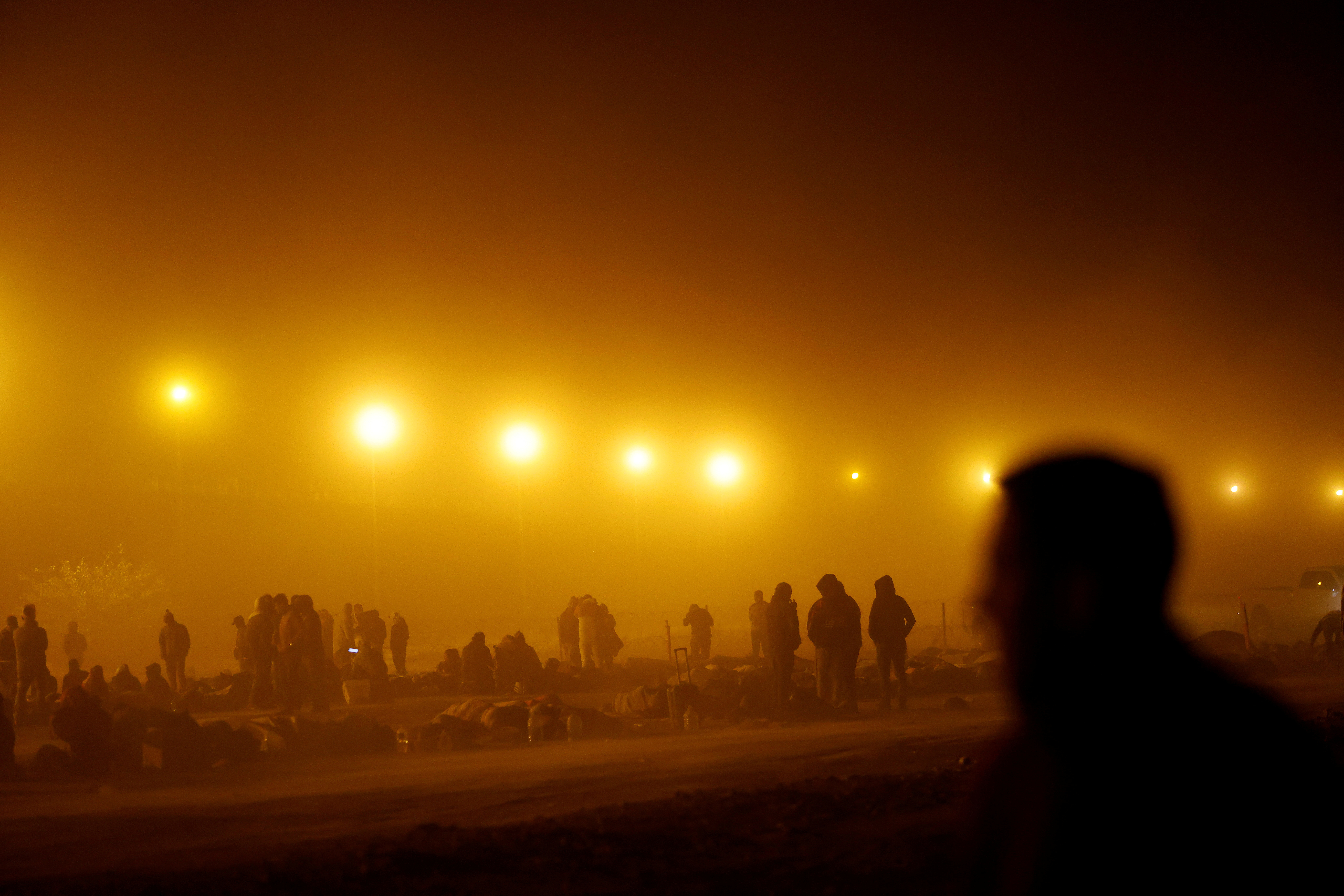 Migrants stand near the border wall during a sandstorm after having crossed the U.S.-Mexico border to turn themselves in to U.S. Border Patrol agents, as the U.S. prepares to lift COVID-19 era Title 42 restrictions that have blocked migrants at the border from seeking asylum since 2020, in El Paso, Texas, U.S., May 10, 2023. 