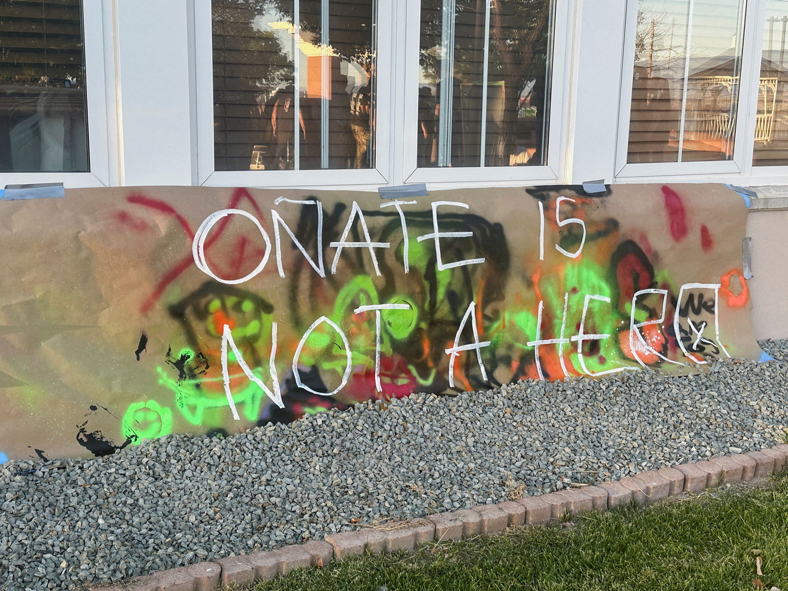 Protesters are reflected on a window as they stand next to a concrete platform where authorities had planned to reinstall a statue of Spanish conquistador Juan de Onate but postponed the event after demonstrators occupied the platform, at the Rio Arriba County Complex in Espanola, New Mexico, U.S., September 27, 2023. 