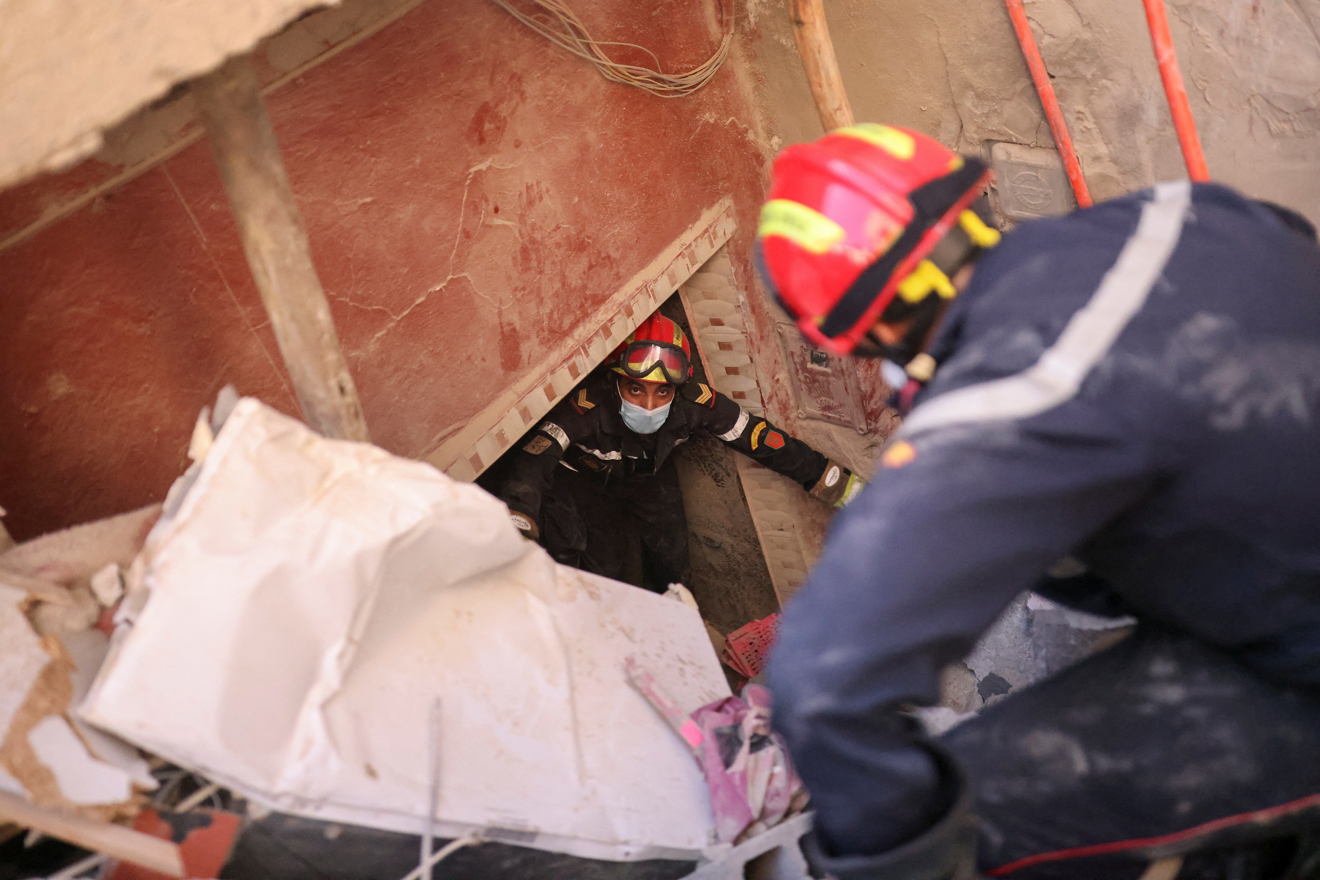Emergency workers attempt to remove a body, inside the destroyed house of Tamo, 80-year-old, in the aftermath of a deadly earthquake, in Amizmiz, Morocco, September 10, 2023. REUTERS/Nacho Doce
