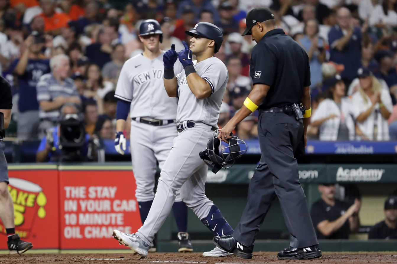 New York Yankees’ DJ LeMahieu, left, looks on as teammate Jasson Dominguez, center, celebrates after they scored on a home run by Dominguez during a baseball game against the Houston Astros, Sunday, Sept. 3, 2023 in Houston. Also in photo: umpire Jeremie Rehak, right.