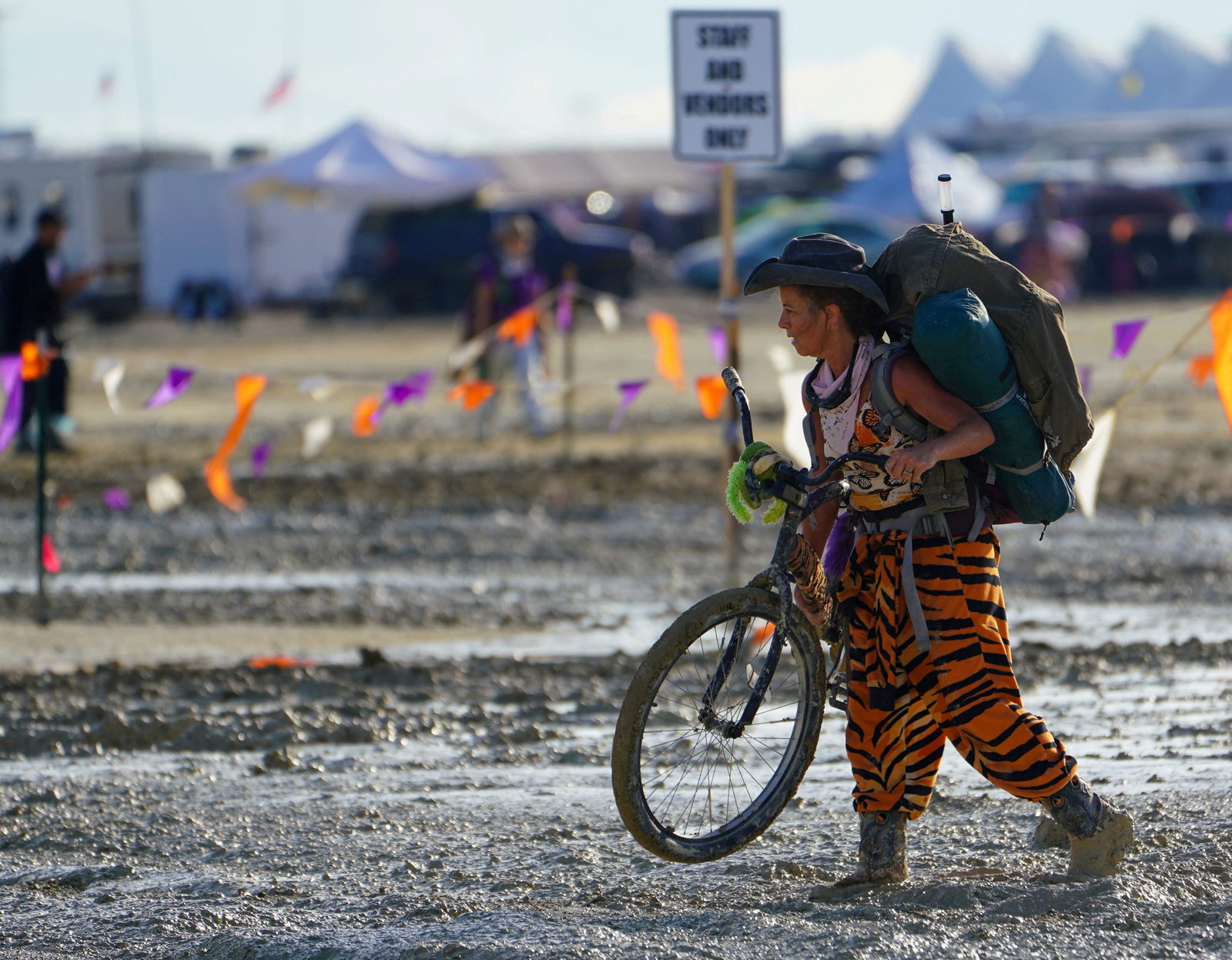 A Burning Man participant walks their bike through the mud near the exit, after a severe rainstorm left tens of thousands of revelers attending the annual festival stranded in mud in Black Rock City, in the Nevada desert September 3, 2023. Trevor Hughes/USA Today Network via REUTERS