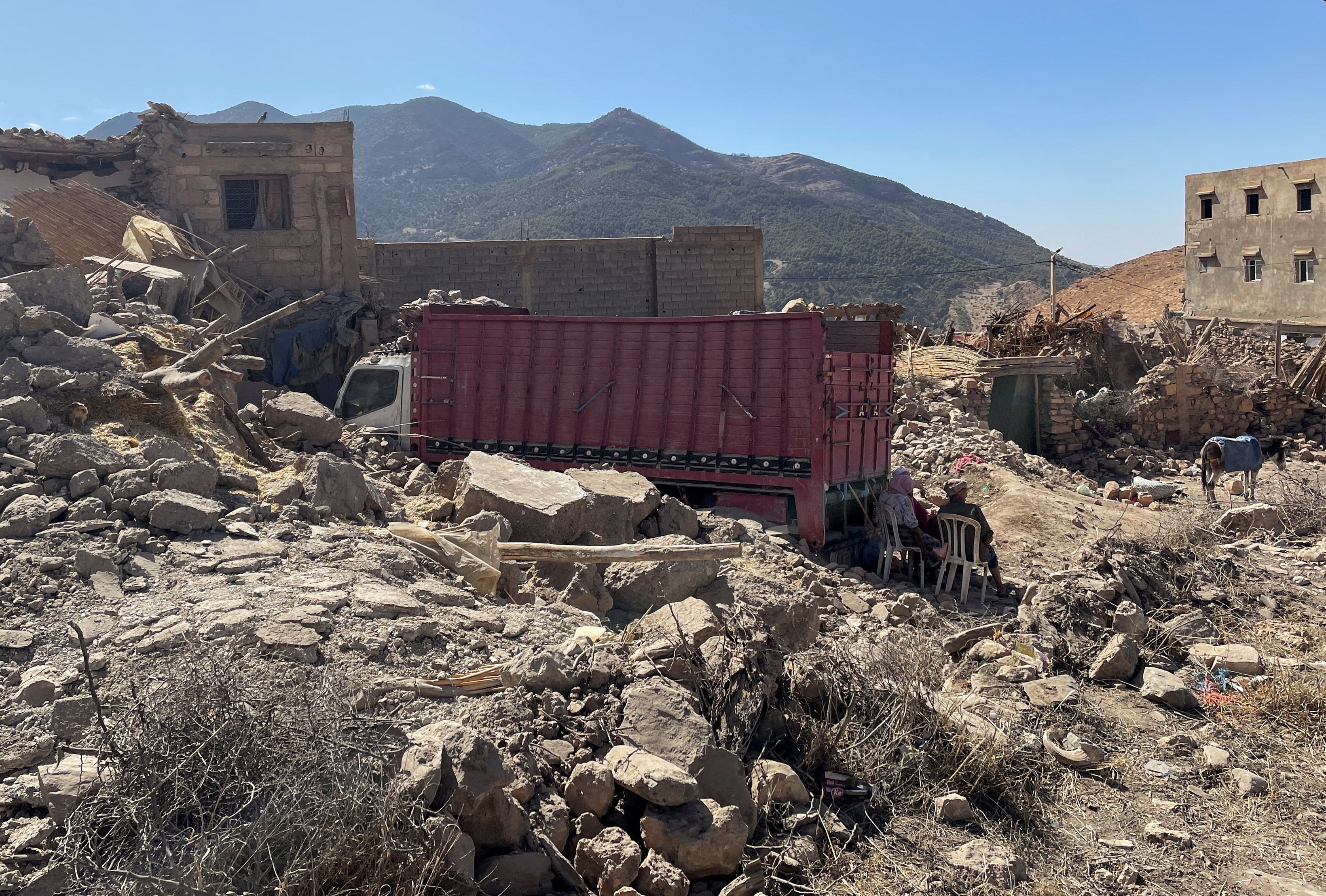People sit near rubble in Tafeghaghte, a remote village of the High Atlas mountains, in the aftermath of a powerful earthquake in Morocco, September 10, 2023. REUTERS/Ahmed El Jechtimi