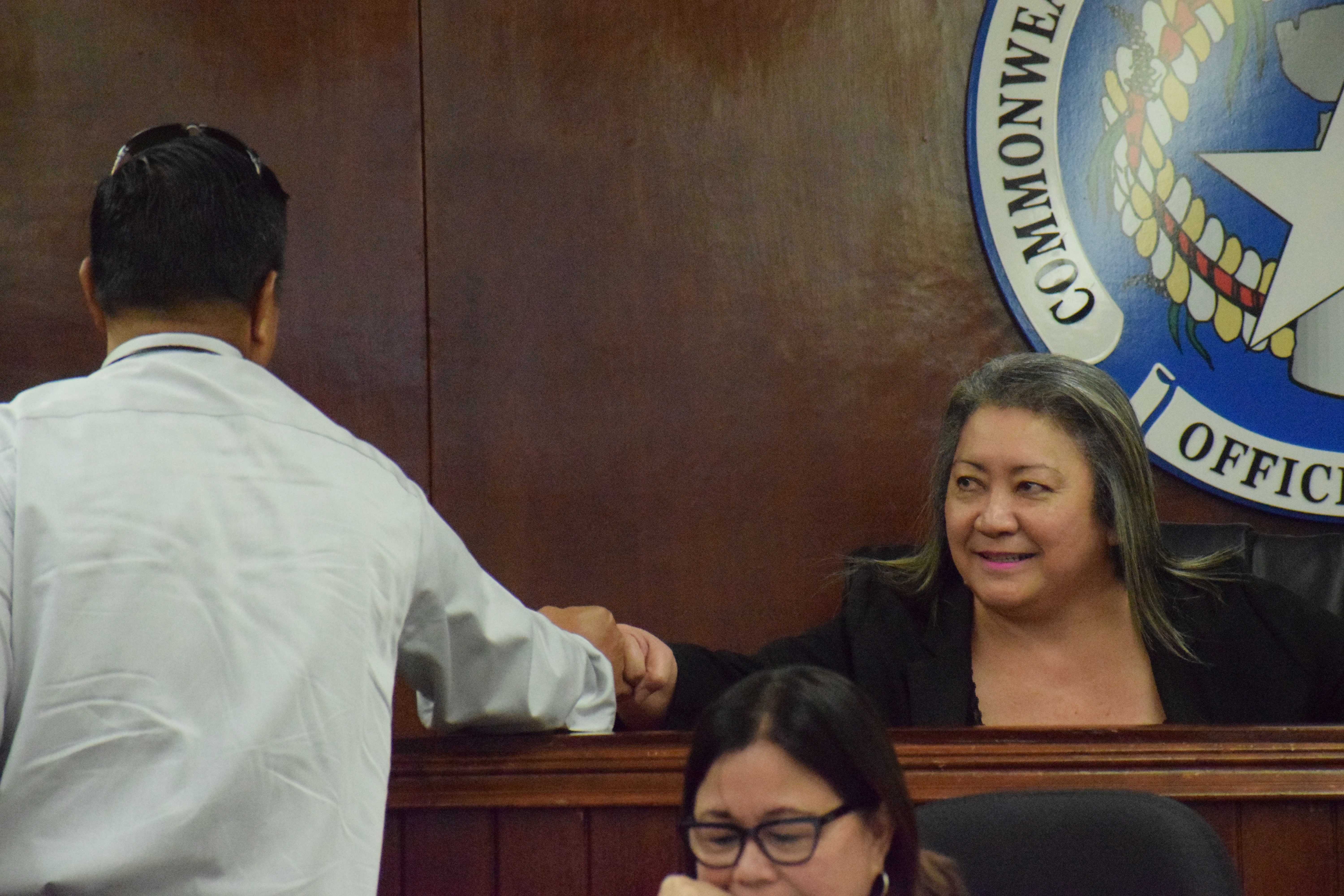 Senate President Edith Deleon Guerrero fist-bumps  Sen. Jude U. Hofschneider prior to the start of an emergency session on Monday.