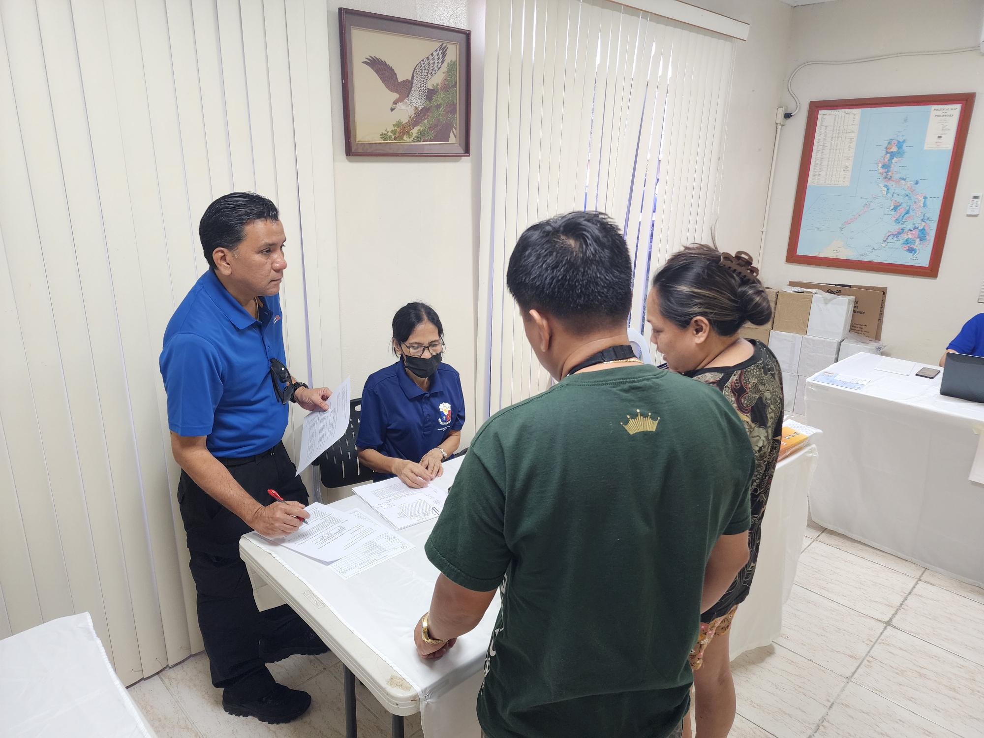 Philippine Consul Joaquin Ricardo Aragon, left, talks with Philippine passport applicants on Saturday.