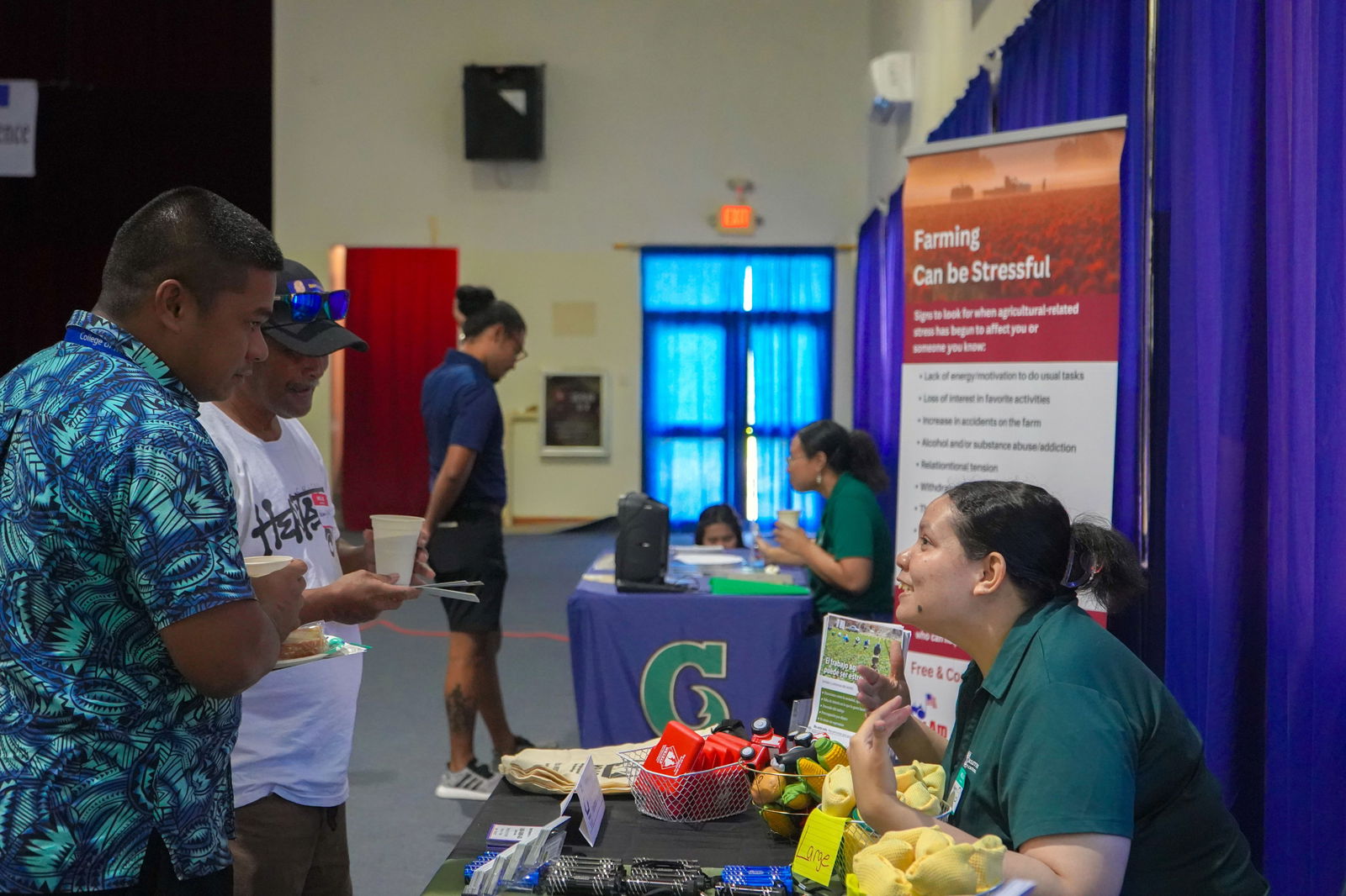 Mary Catherine Wiley, a UOG extension assistant who is certified in Mental Health First Aid and QPR for suicide prevention, shares mental health resources with two attendees of the Pohnpei Farmer Focus Conference on June 28, 2023.