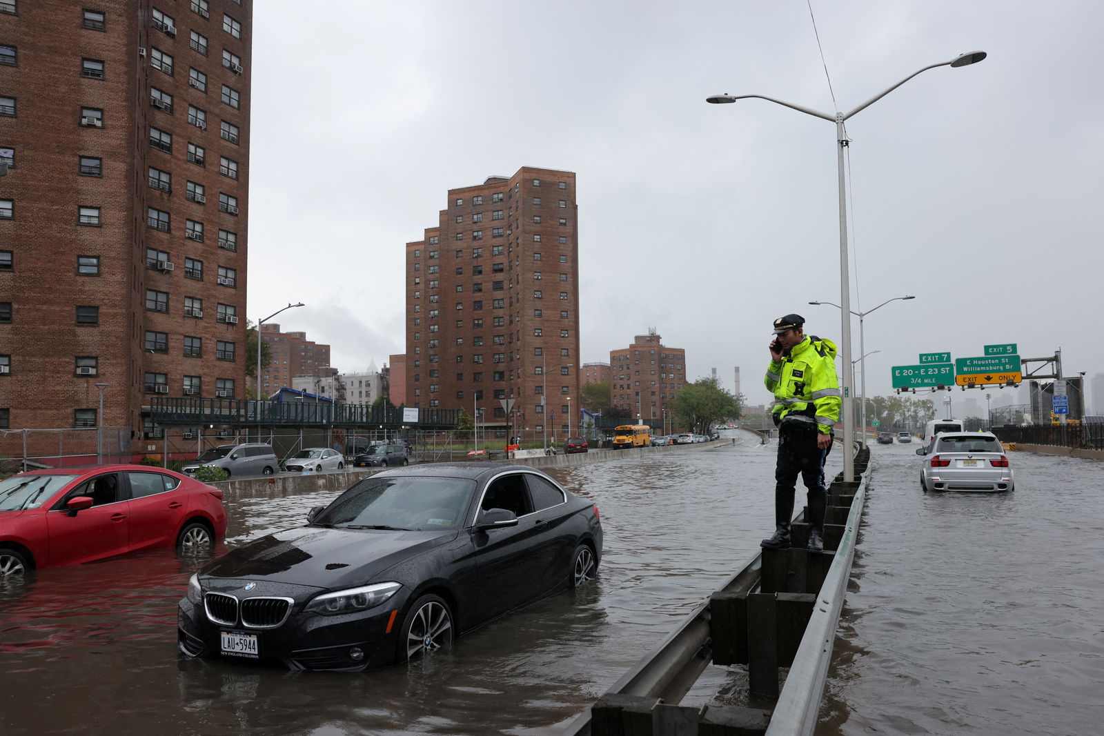 A police officer from the NYPD Highway Patrol uses his mobile phone next to cars stuck in a flooded street after heavy rains as the remnants of Tropical Storm Ophelia bring flooding across the mid-Atlantic and Northeast, at the FDR Drive in Manhattan near the Williamsburg Bridge, in New York City, U.S., September 29, 2023. 