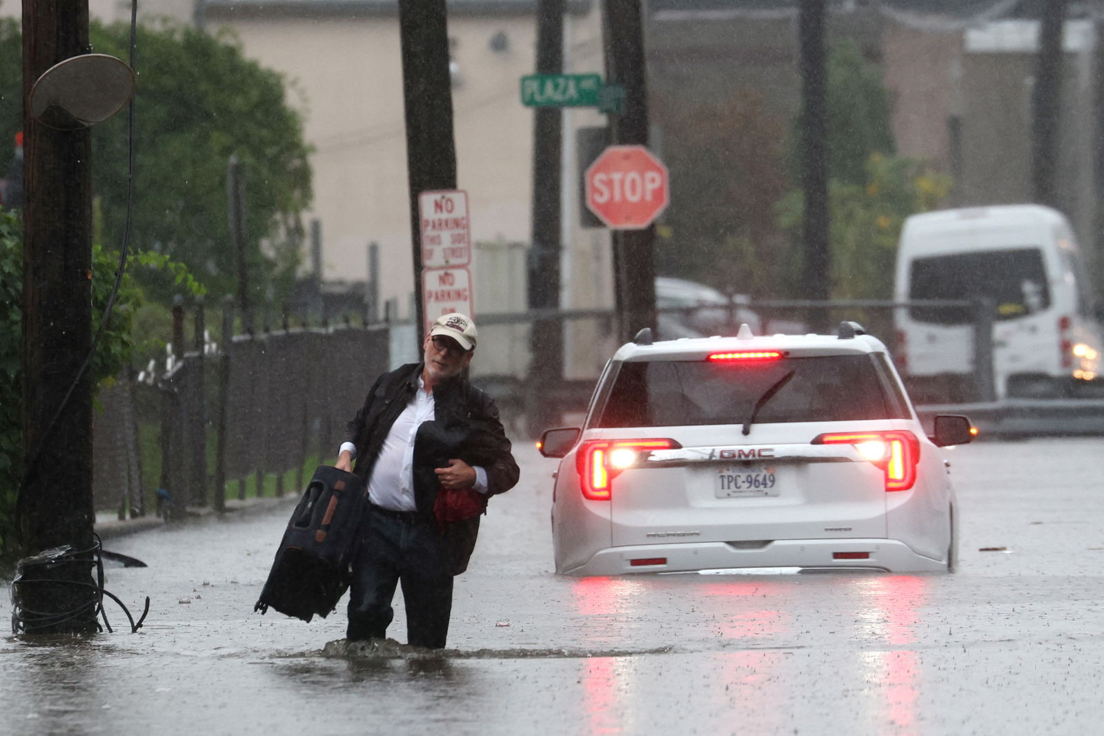 A man carries his belongings as he abandons his vehicle which stalled in floodwaters during a heavy rain storm in the New York City suburb of Mamaroneck in Westchester County, New York, U.S., September 29, 2023. 