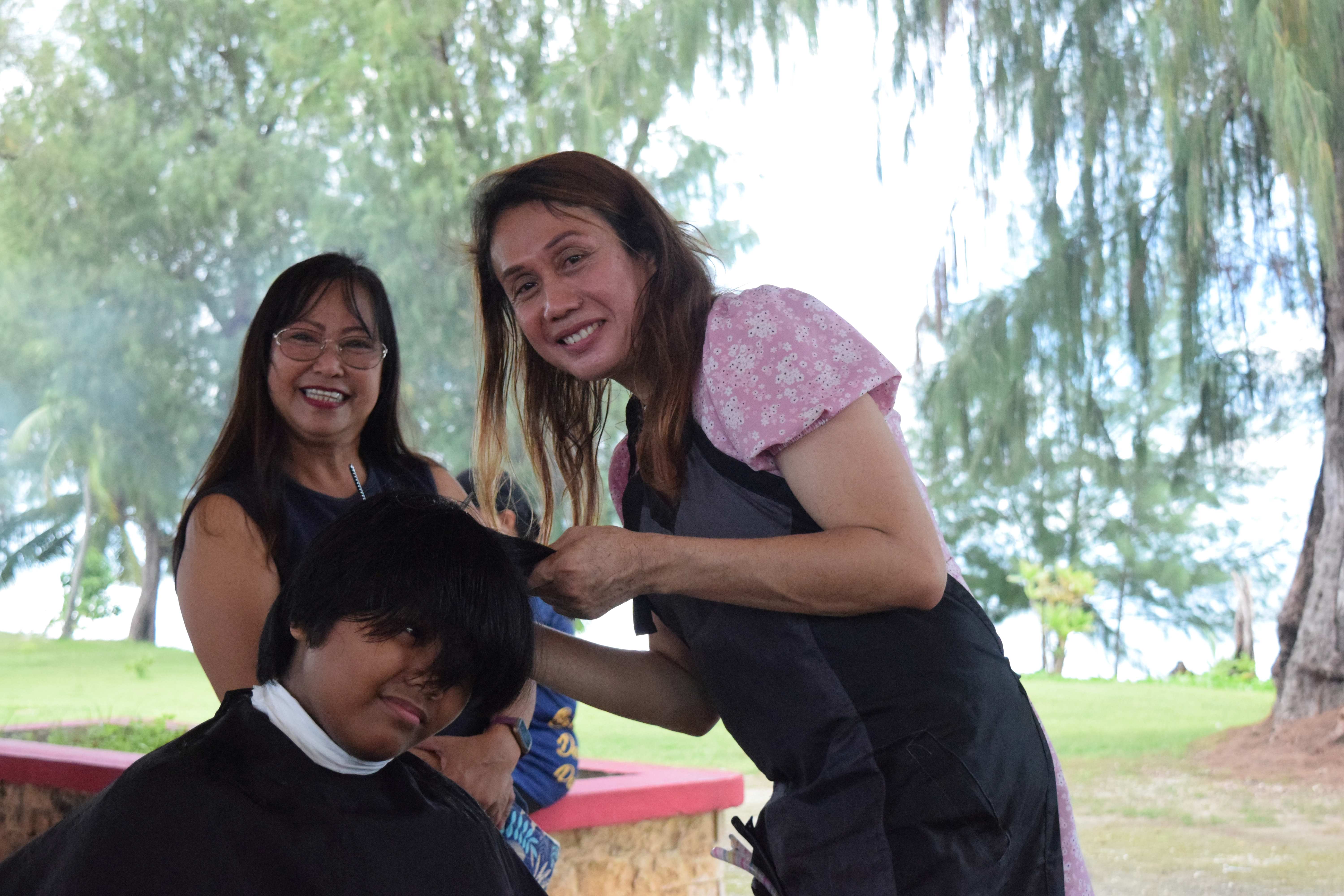 Mommyla Spa & Salon hairstylist Sharmaine Casquero gives a boy a haircut during the back-to-school free hair cut event organized by the Saipan Magahaga Lady Eagles Group at the Minatchom Atdao pavilion on Aug. 20, 2023.