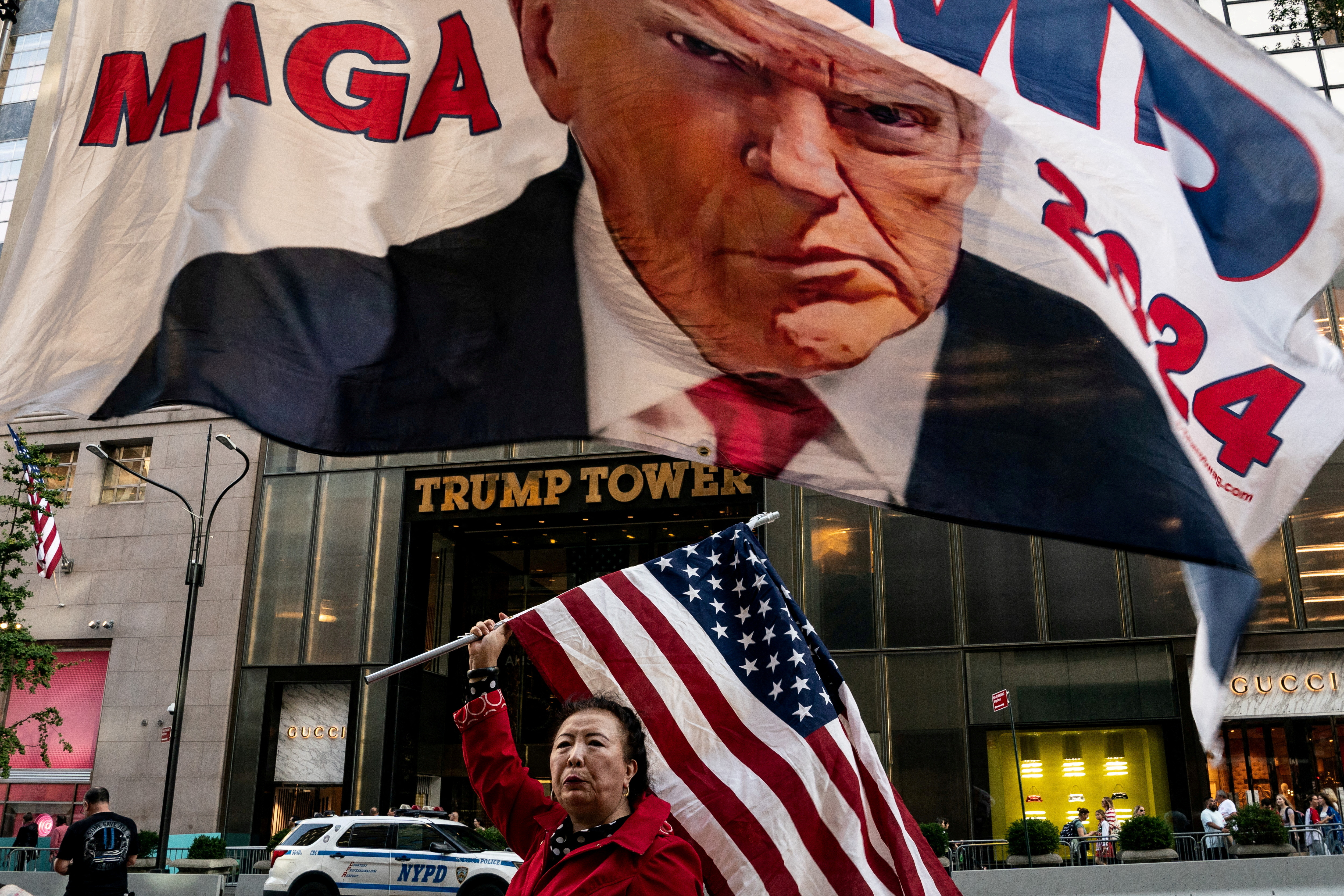 A supporter of former U.S. President Donald Trump holds up a U.S. national flag at Trump Tower in New York City, U.S., October 1, 2023. 