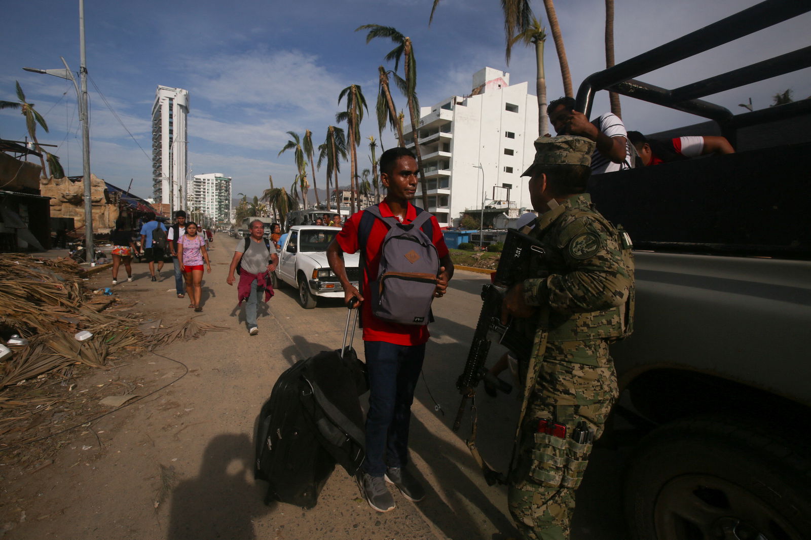 People walk near damaged buildings next to member of a military, in the aftermath of Hurricane Otis, in Acapulco, Mexico, October 28, 2023. 
