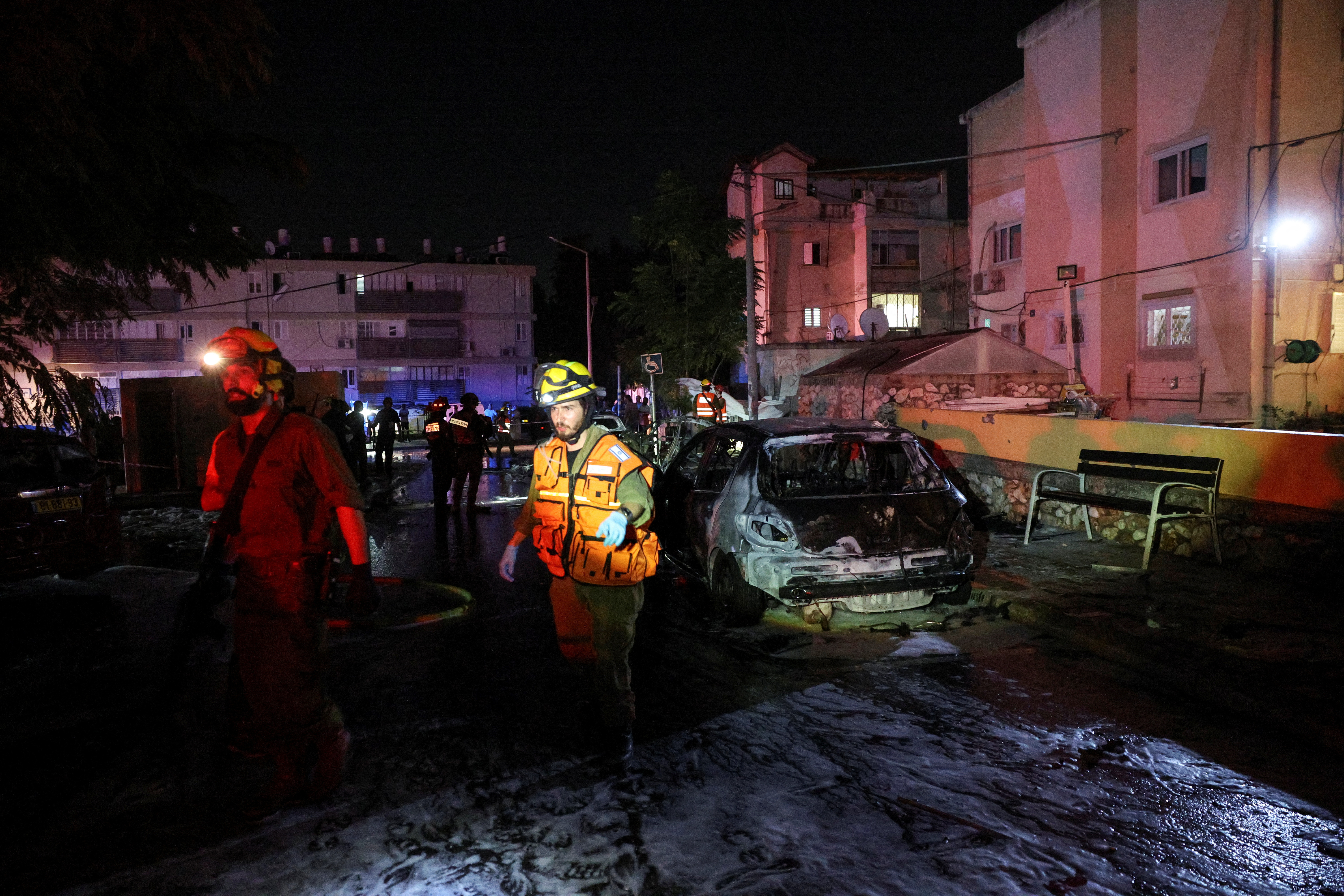Israeli soldiers walk next to a burnt car following a rocket attack from the Gaza Strip that landed in Ashkelon, southern Israel October 20, 2023. 