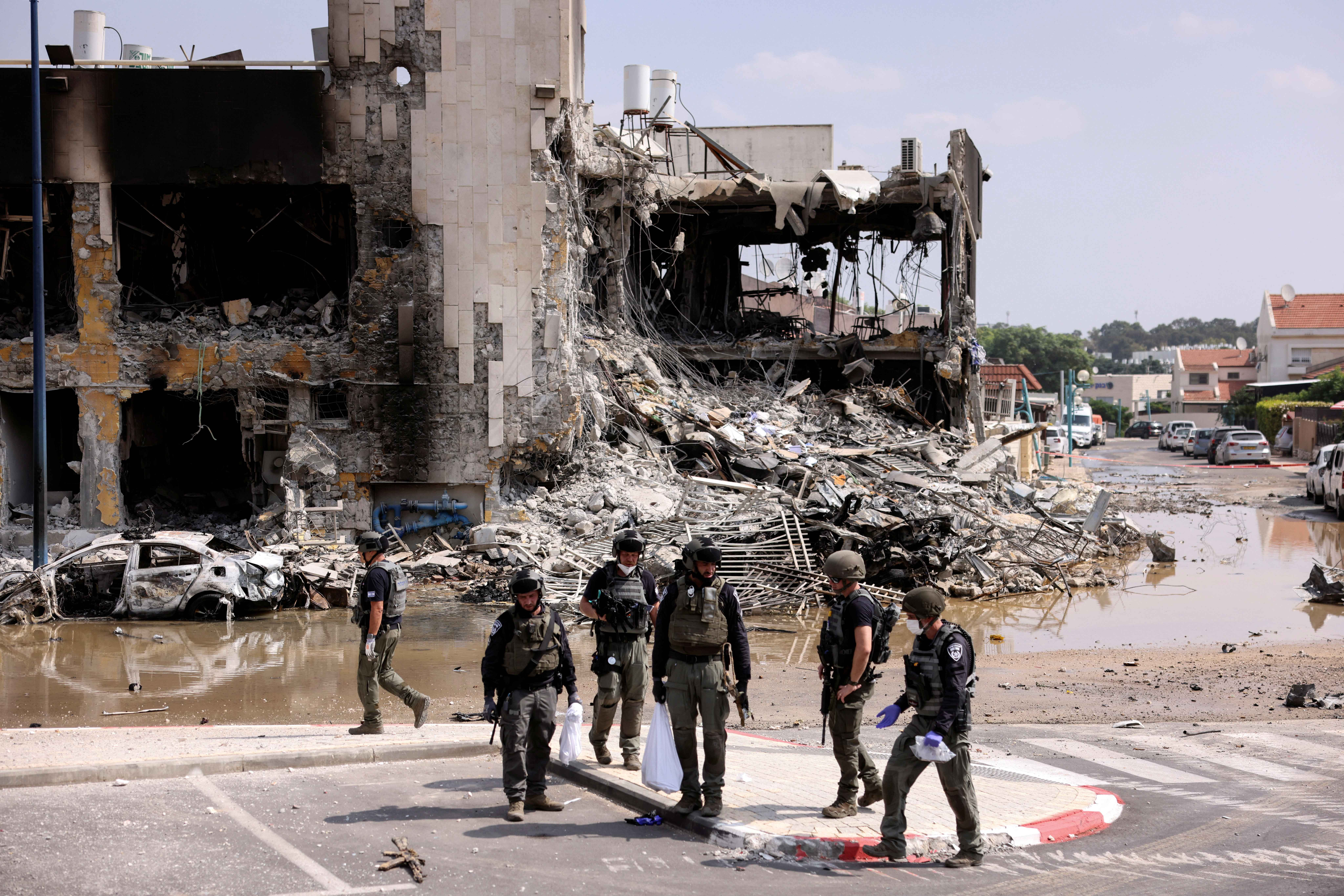 Israeli security gather near a rifle at the site of a battle following a mass infiltration by Hamas gunmen from the Gaza Strip, in Sderot, southern Israel October 8, 2023.
