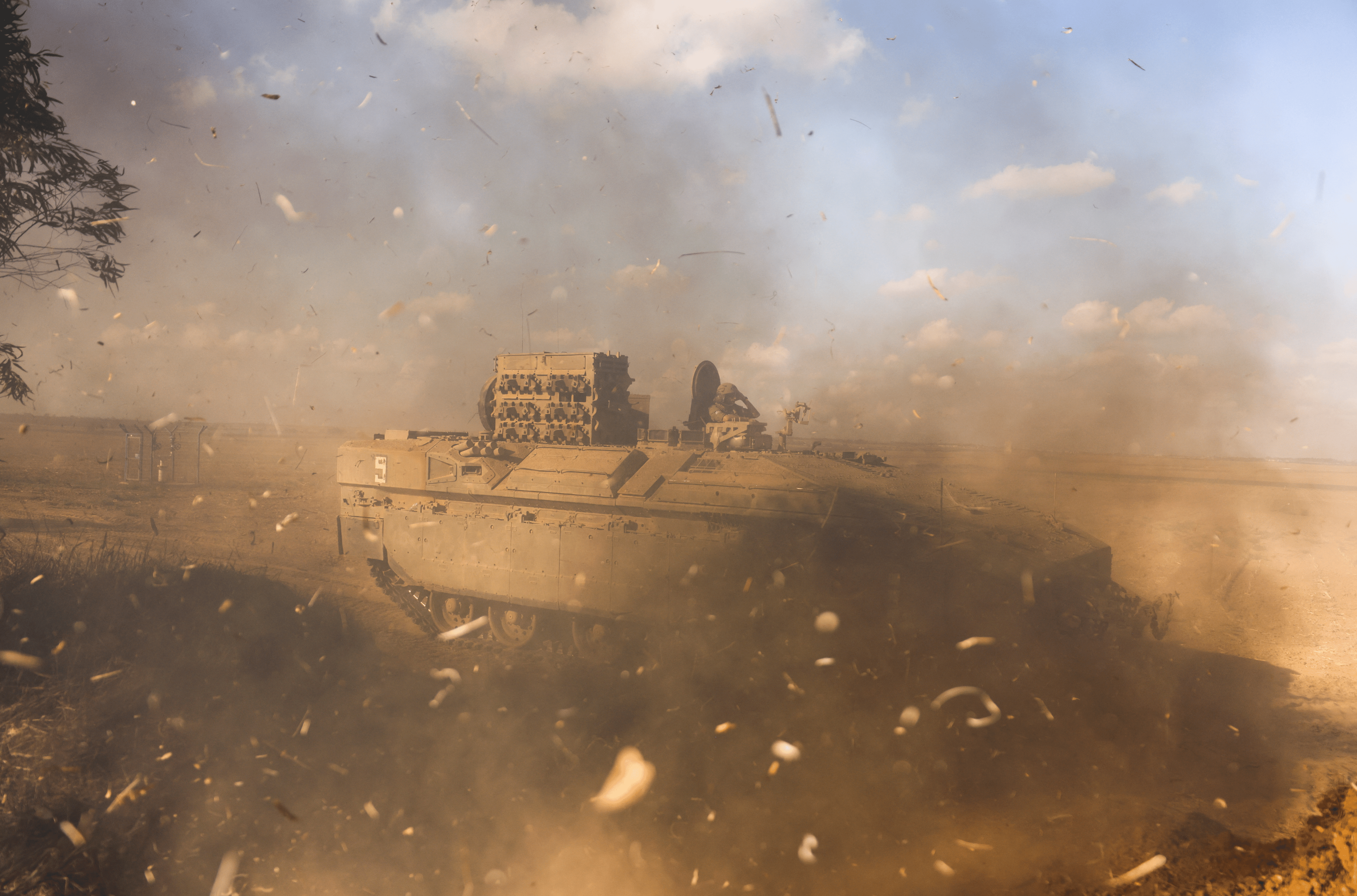 An Israeli Armoured Personnel Carrier (APC) is obscured as it whips up dust near Israel's border with the Gaza Strip, in southern Israel October 15, 2023. 