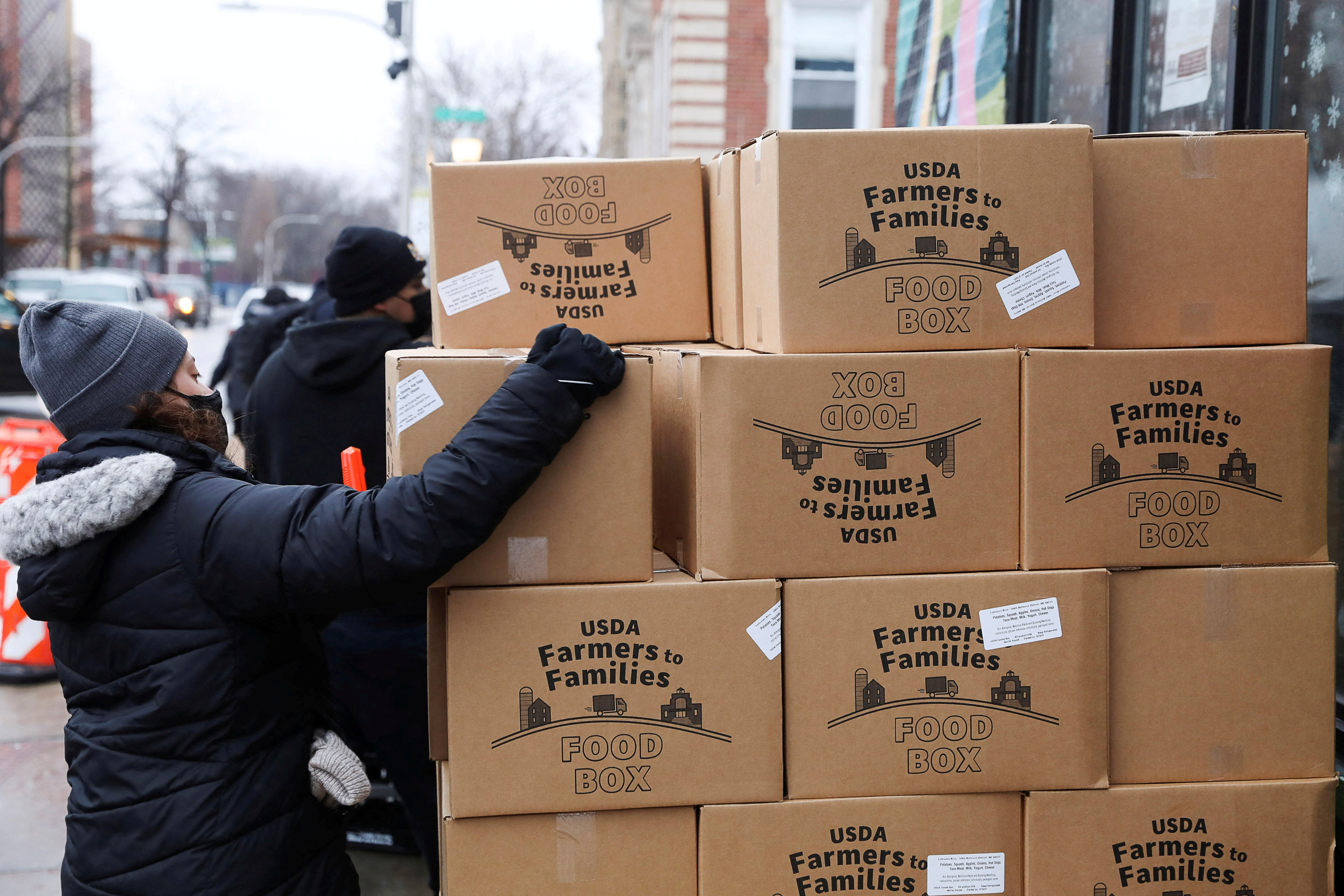 Ellie Amador picks up a United States Department of Agriculture (USDA) Farmers to Families food box as food is distributed at the nonprofit New Life Centers' food pantry in Chicago, Illinois, U.S. March 16, 2021. 