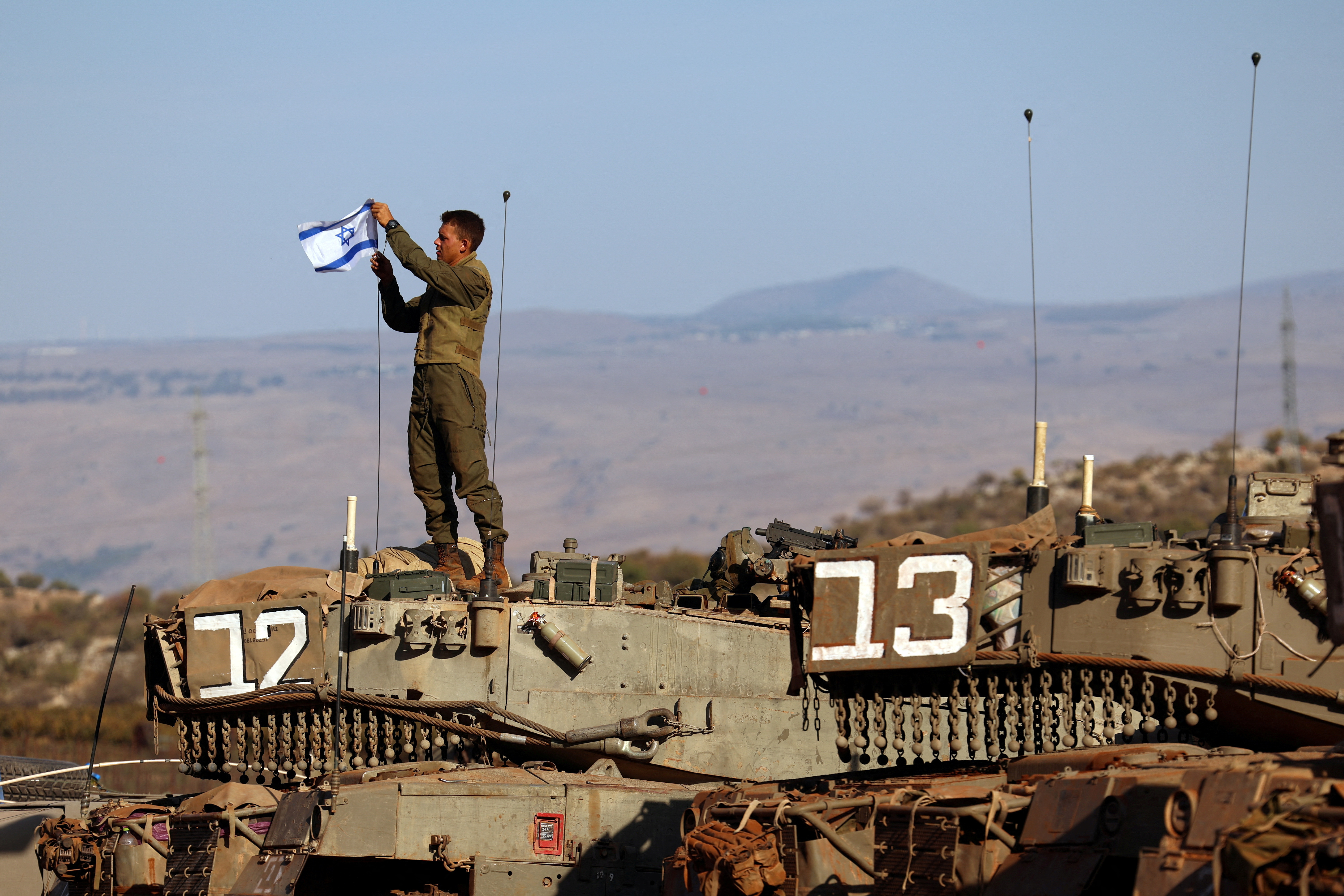 A soldier installs an Israeli flag on a tank during a military drill near Israel's border with Lebanon in northern Israel, October 26, 2023. 