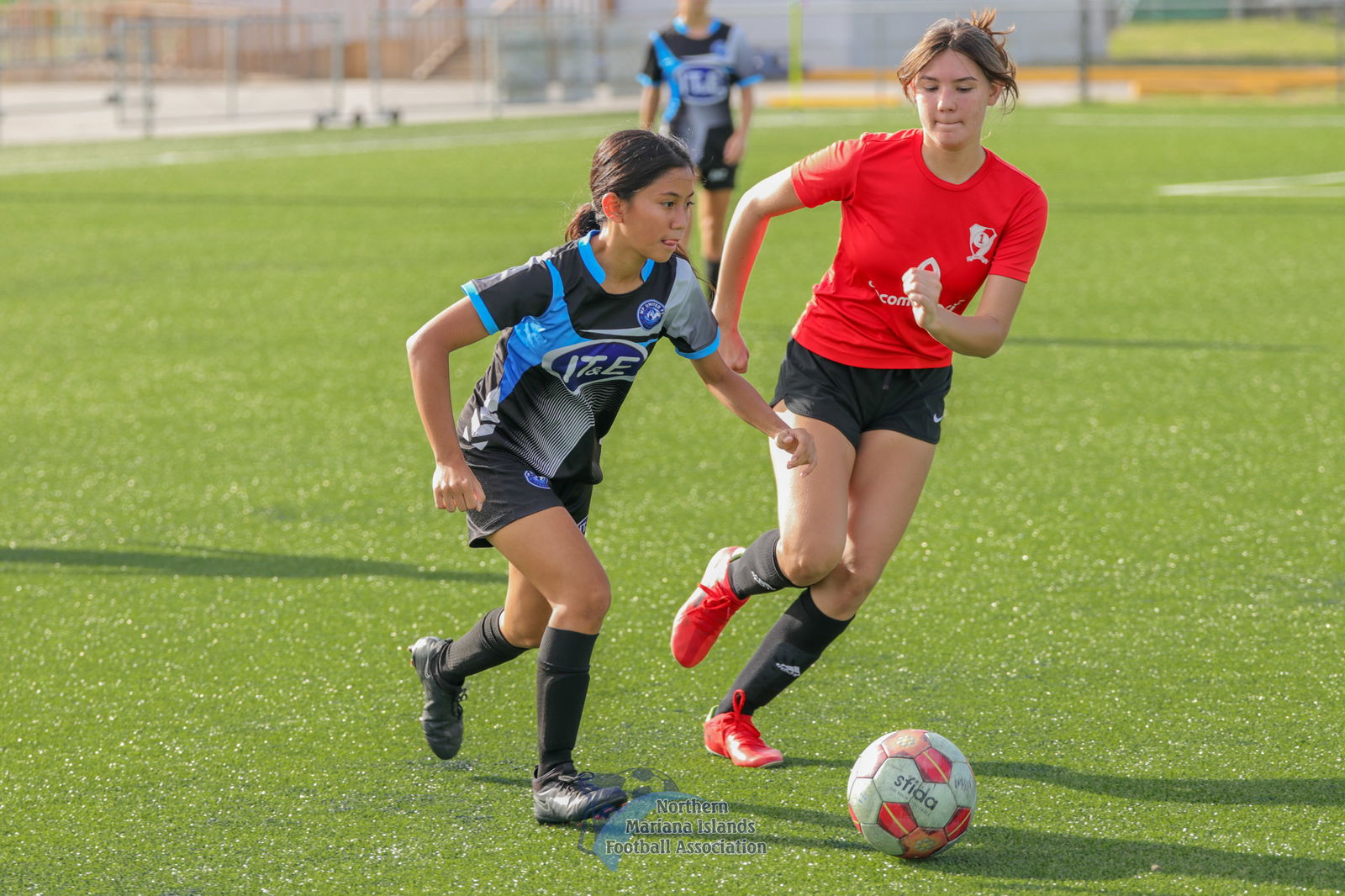 MP United's Matty Angeles dribbles forward as a Paire defender closes in during a U17 girls division game of the TakeCare Youth Soccer League Fall 2023 at the NMI Soccer Training Center in Koblerville.