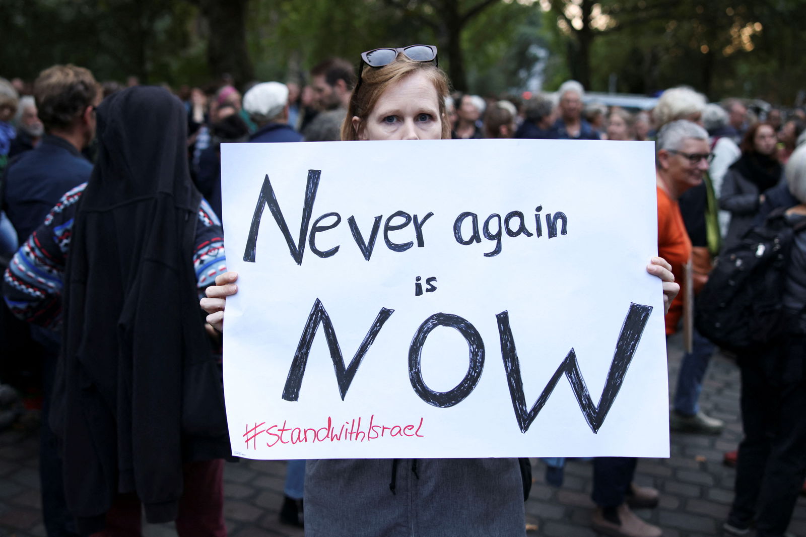 A woman holds a sign during a vigil in front of the Fraenkelufer synagogue in Berlin, Germany, October 13, 2023. REUTERS/Liesa Johannssen