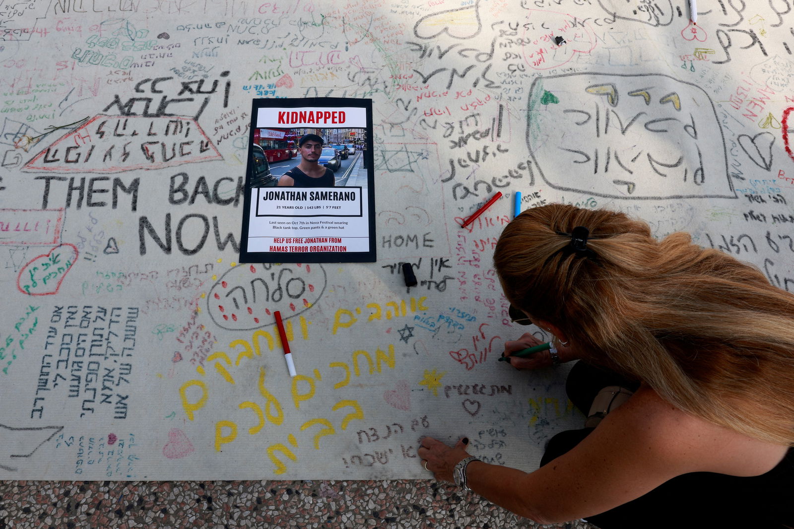 A woman writes a message during a demonstration by family members and supporters of hostages who are being held in Gaza after they were kidnapped from Israel by Hamas gunmen, as they call for a dialogue with Israeli Prime Minister Benjamin Netanyahu and Defence Minister Yoav Gallant, in Tel Aviv, Israel October 28, 2023. 