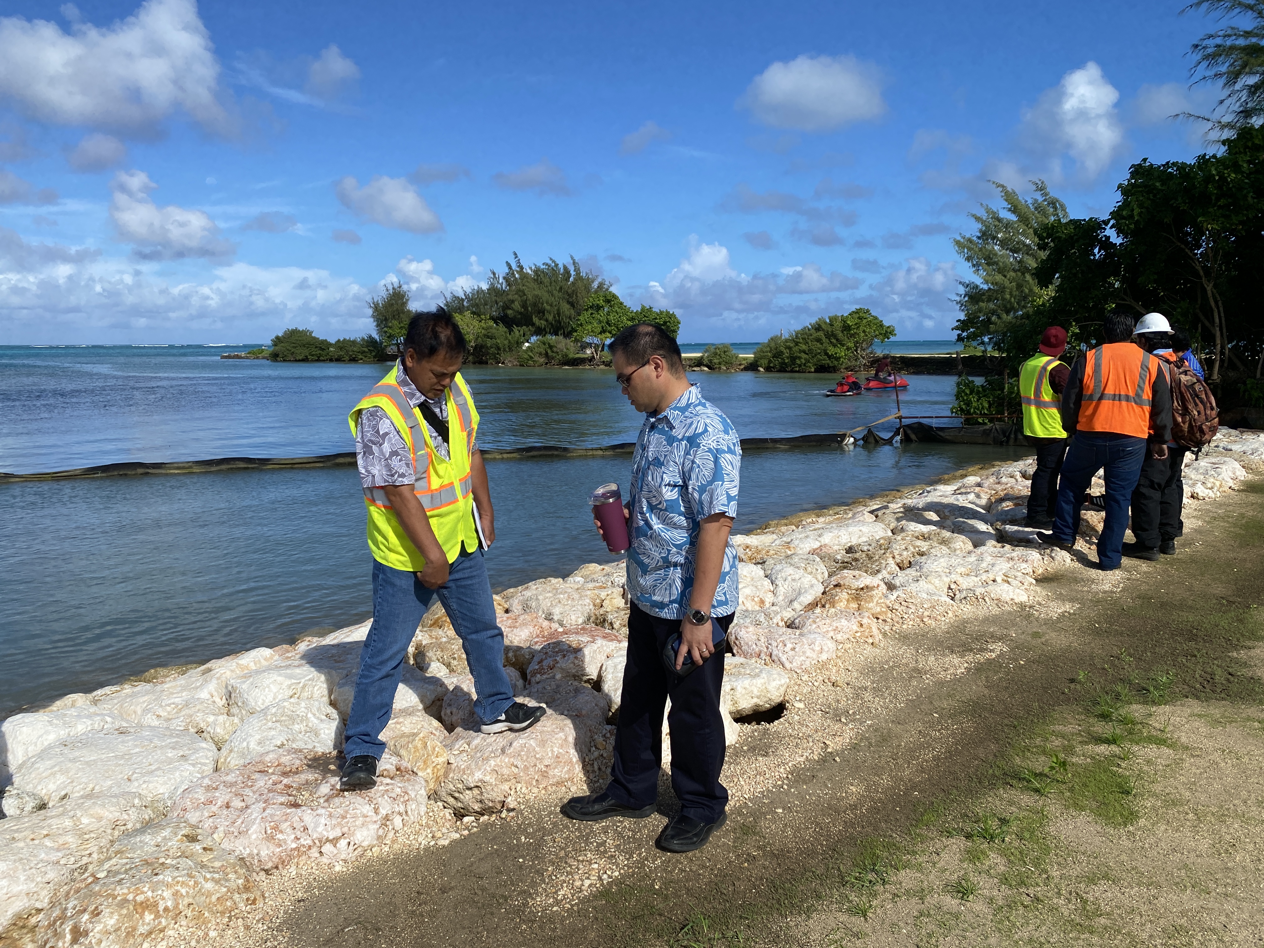 While Department of Land and Natural Resources Secretary Sylvan Igisomar, right, looks on, Department of Public Works highway engineer Gani Salazar, left, points to an area where runoff has removed vacuum material at the Garapan Fishing Base Shoreline Revetment project. 