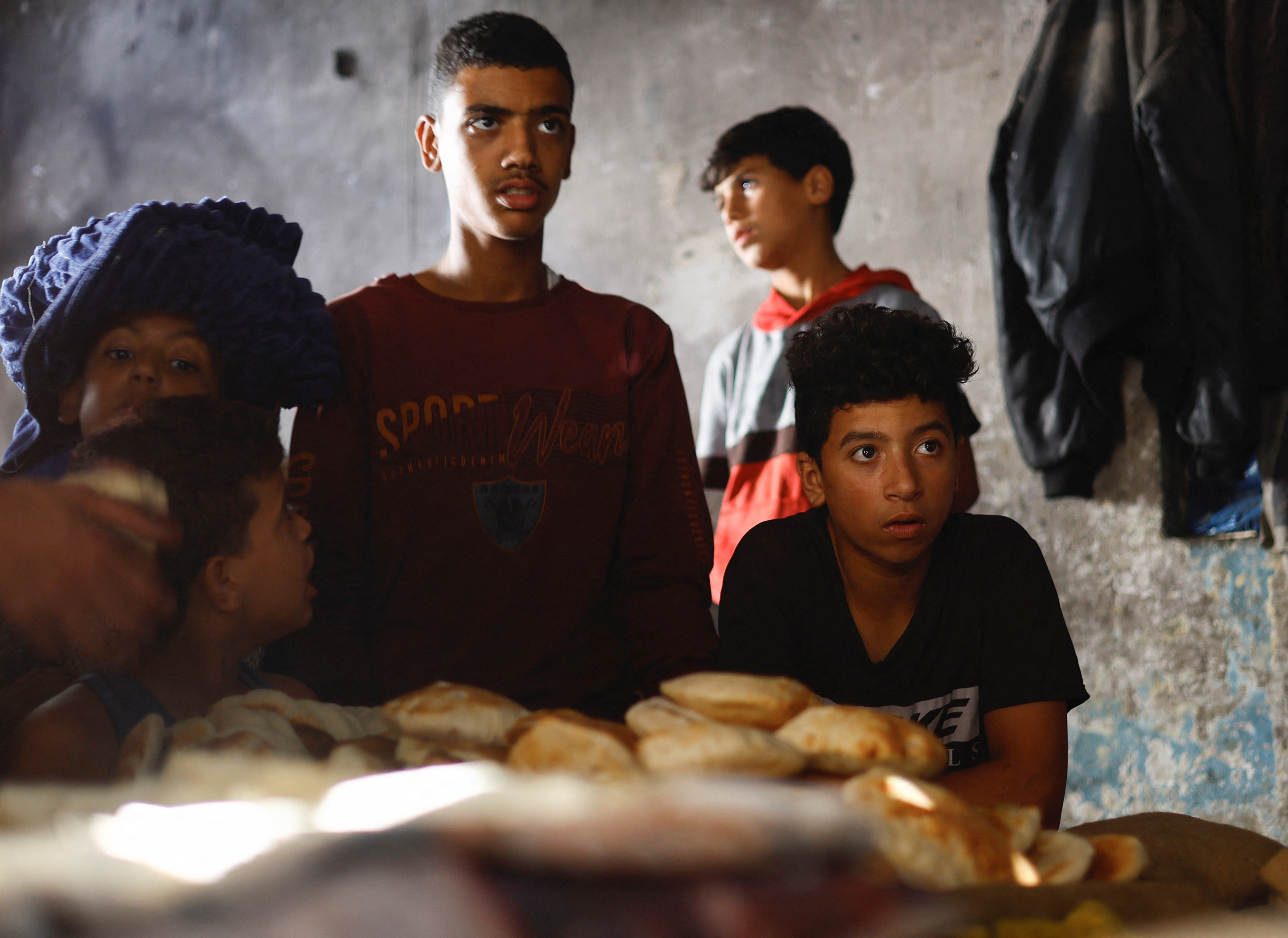 Palestinians wait for bread baked on firewoods, amid fuel and power shortages, as the conflict between Hamas and Israel continues, in Khan Younis in the southern Gaza Strip, October 16, 2023. 