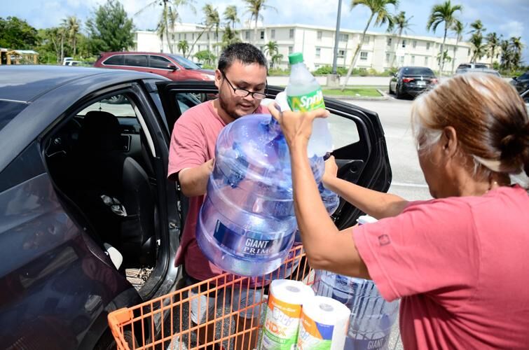 From left: Jose Quitugua helps his mother, Frances Quitugua, load empty water bottles and other supplies into their vehicle Monday, Oct. 9, 2023, at the Home Depot. 