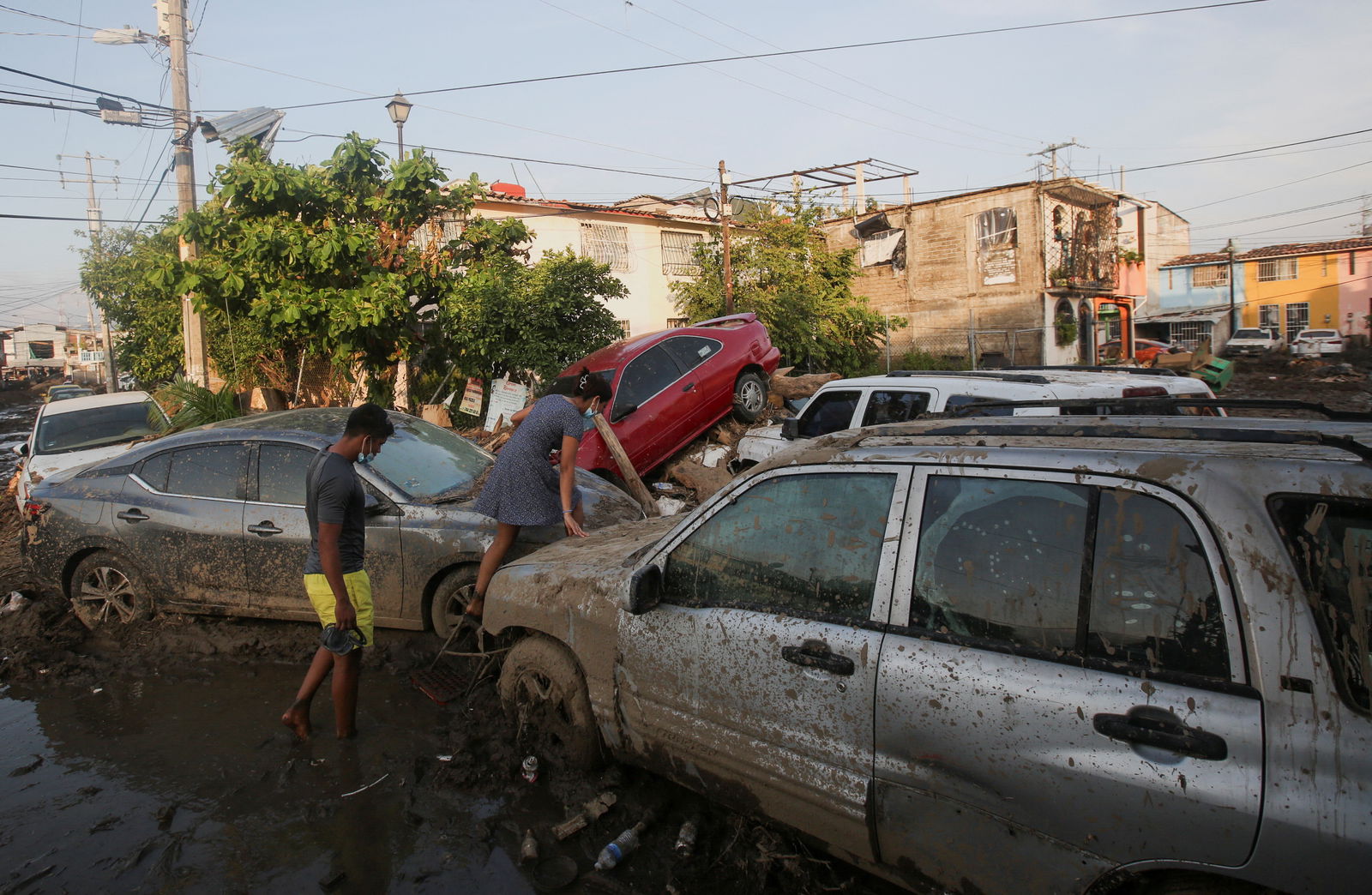 A woman climbs over a car stuck in the mud, in the aftermath of Hurricane Otis, in Acapulco, Mexico, October 29, 2023. 