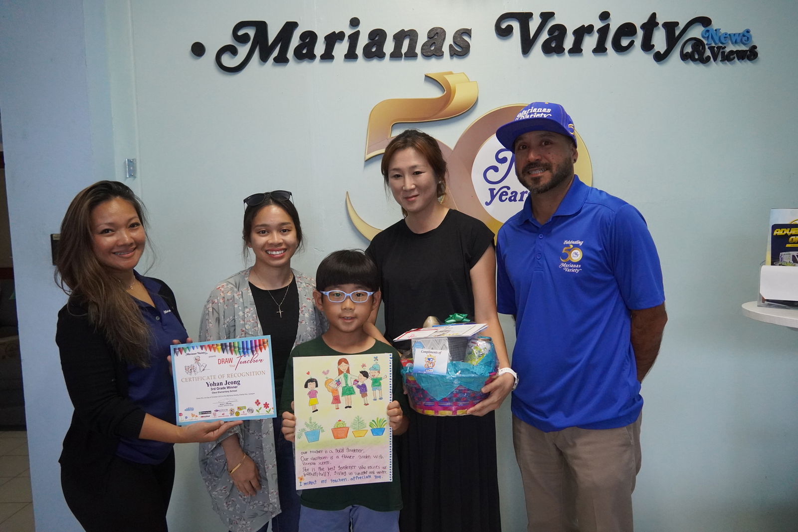 Yohan Jeong receives his prize package for his colorfully detailed work of art with his mother and teacher.