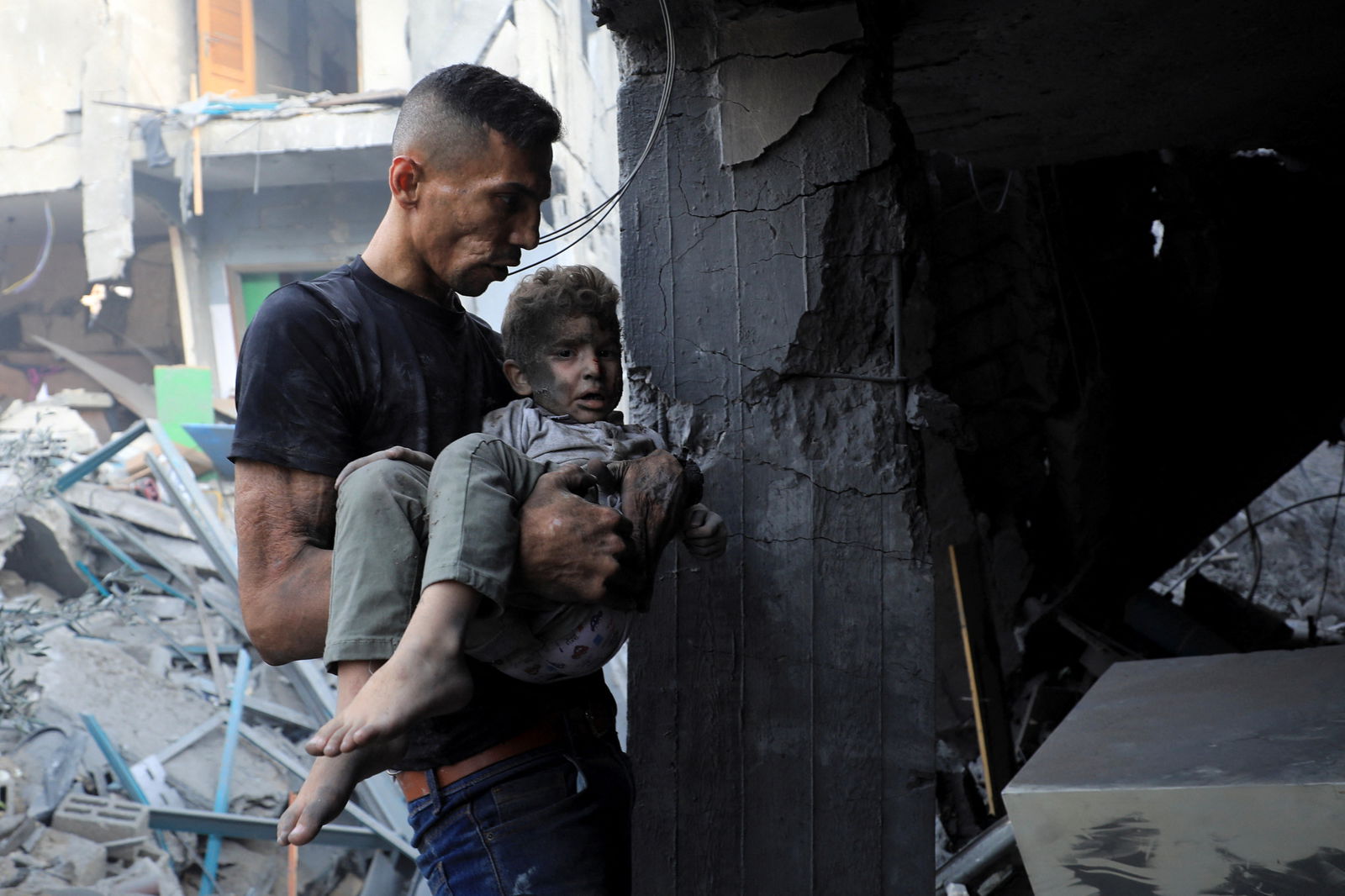A man carries a child as Palestinians search for casualties at the site of an Israeli strike on a residential building in Gaza City October 25, 2023. 