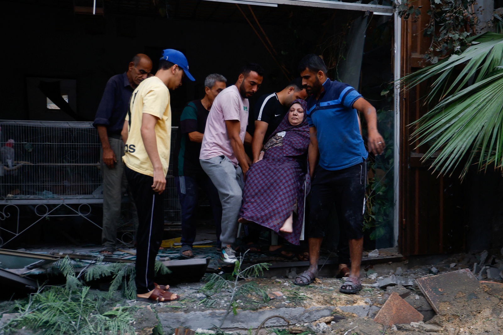 Palestinians carry a woman outside a damaged buidling in the aftermath of Israeli strikes, following a Hamas surprise attack, at Beach refugee camp, in Gaza City, October 9, 2023. 