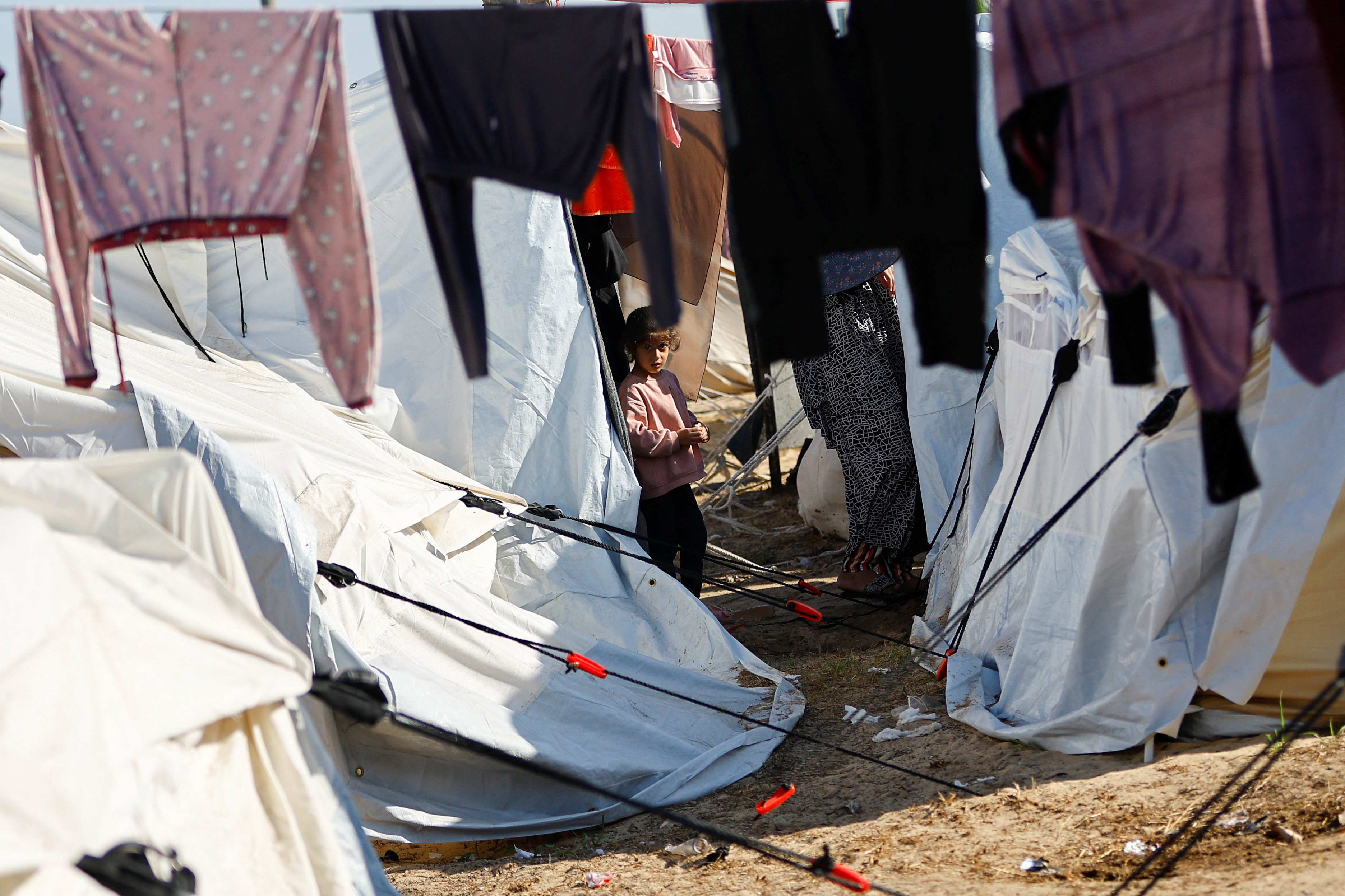 A Palestinian girl, who fled her house amid Israeli strikes, takes shelter at a tent camp at a United Nations-run center, after Israel's call for more than 1 million civilians in northern Gaza to move south, in Khan Younis in the southern Gaza Strip, October 26, 2023. 
