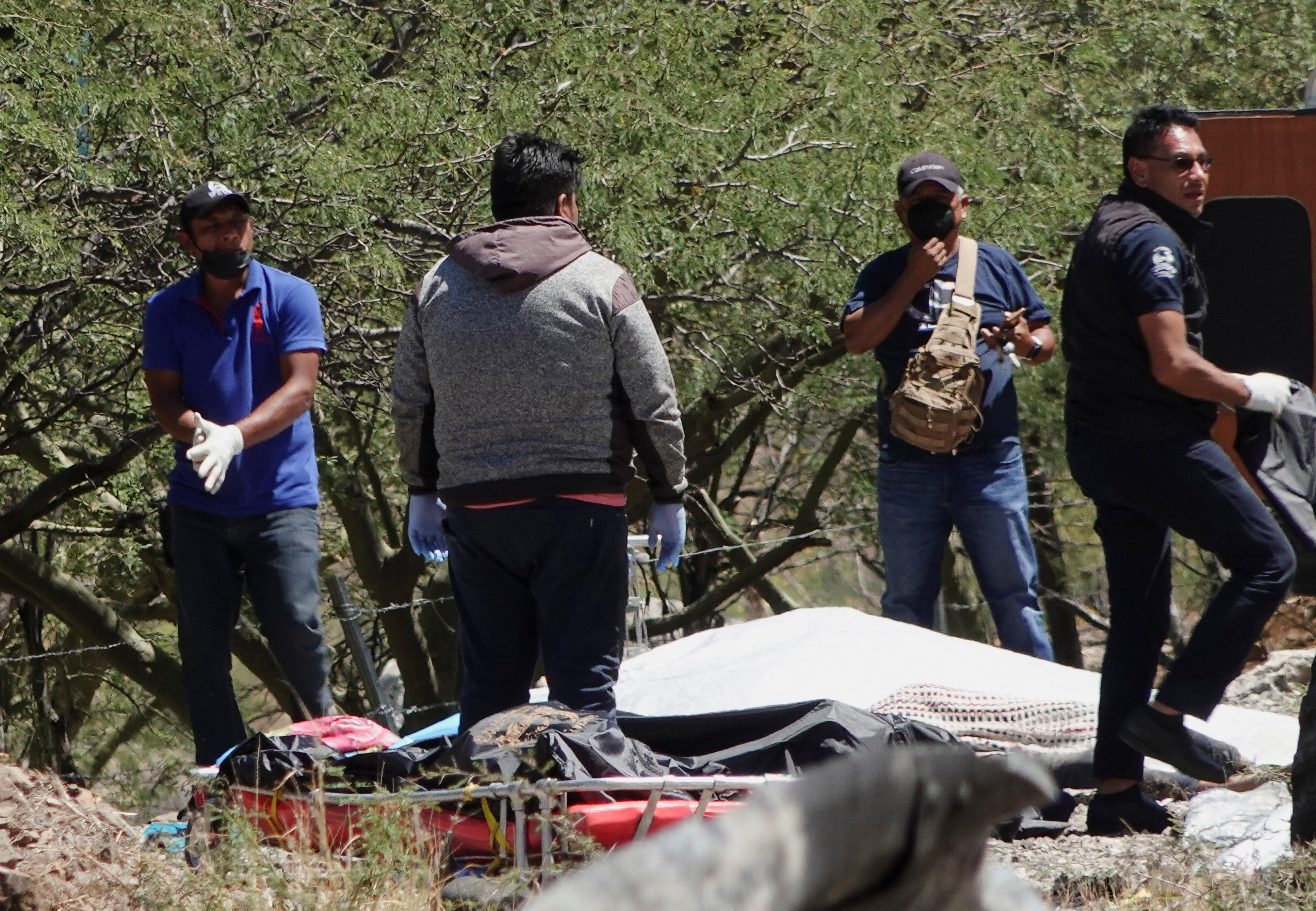 Investigators from the Oaxaca Prosecutor's Office work next to a covered body on the scene of a road accident, after a bus carrying dozens of mostly Venezuelan migrants crashed, which left some of the passengers dead and wounded others, on the highway near Tepelmeme Villa de Morelos, in the southern state of Oaxaca, Mexico October 6, 2023.