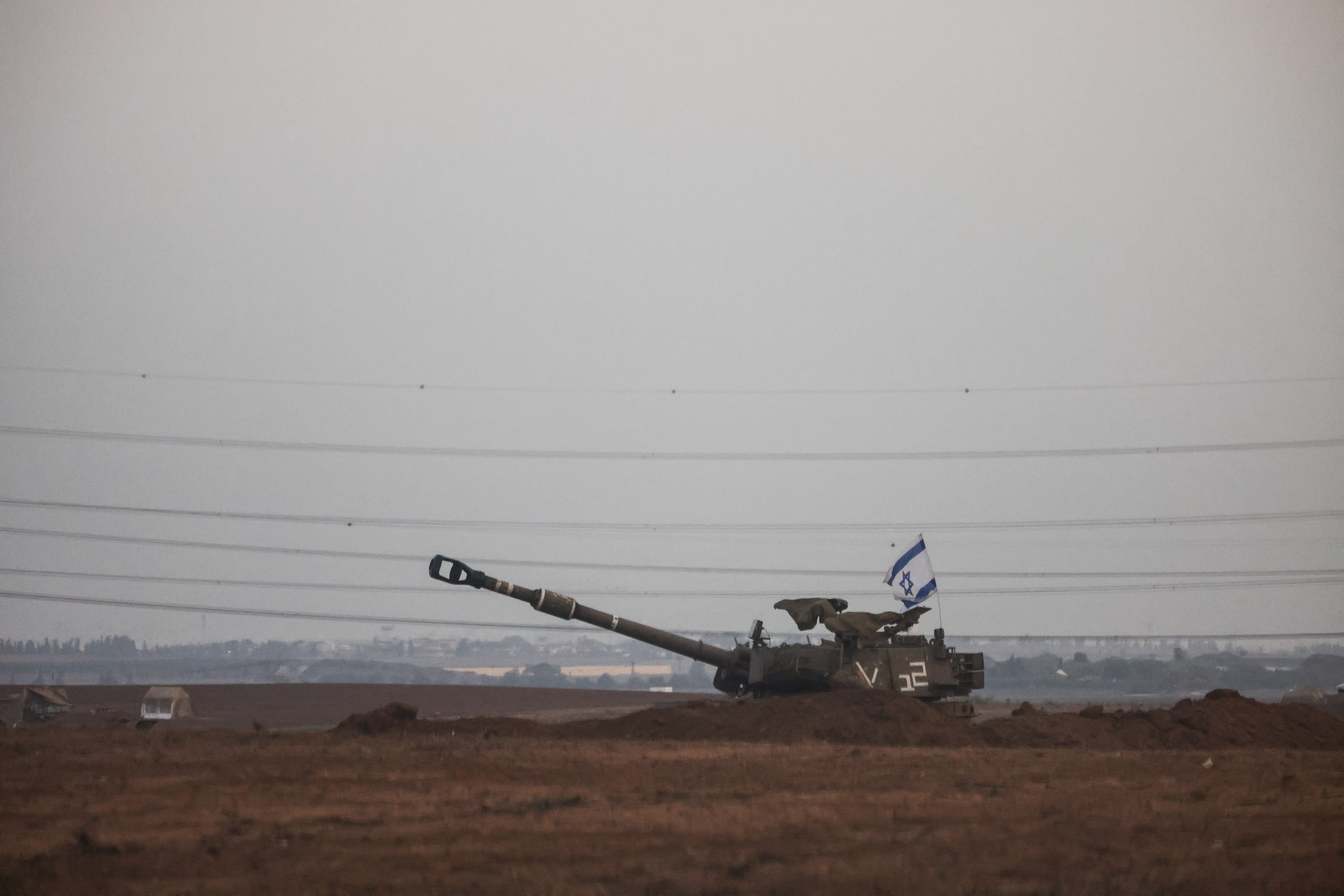 An Israeli flag flutters from a self-propelled howitzer near Israel's border with the Gaza Strip, in southern Israel, October 22, 2023. 