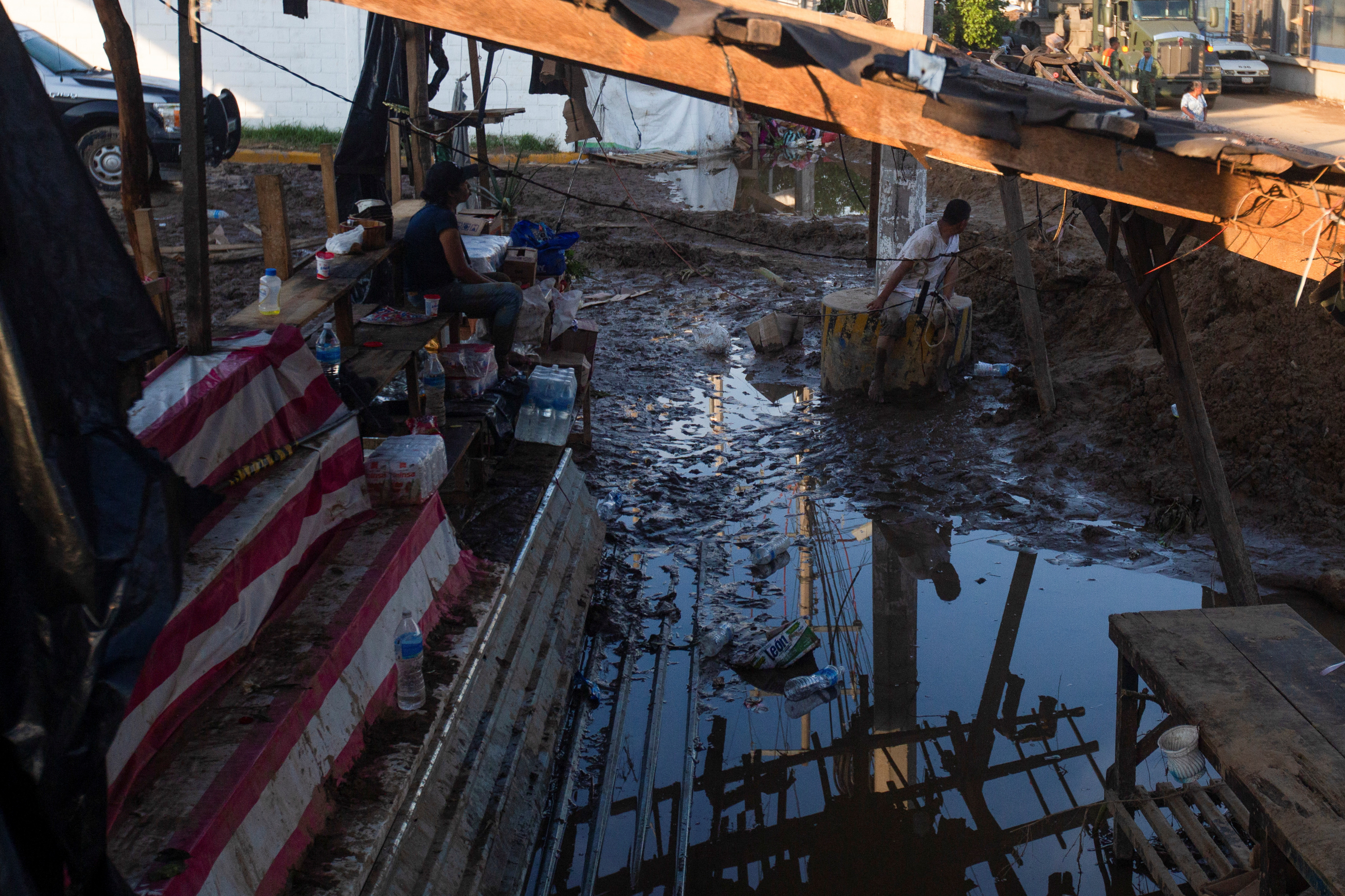 People sit under a damaged structure in the aftermath of Hurricane Otis near Acapulco, Mexico, October 26, 2023. 