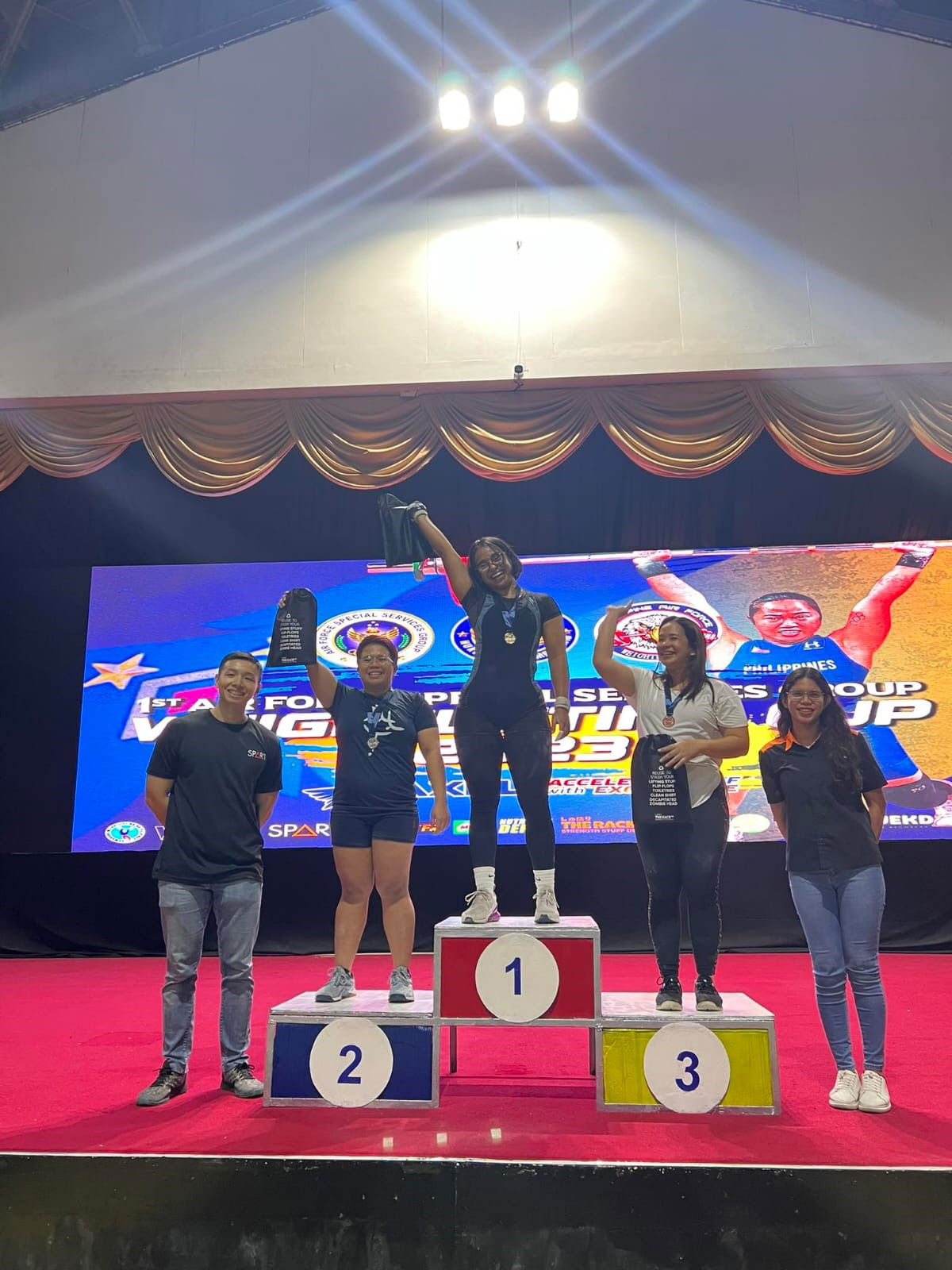 Cheyanne Manuel, center, poses after winning gold in the 1st Airforce Special Service Group Weightlifting Competition 2023 in Pasay City, Metro Manila, the Philippines.